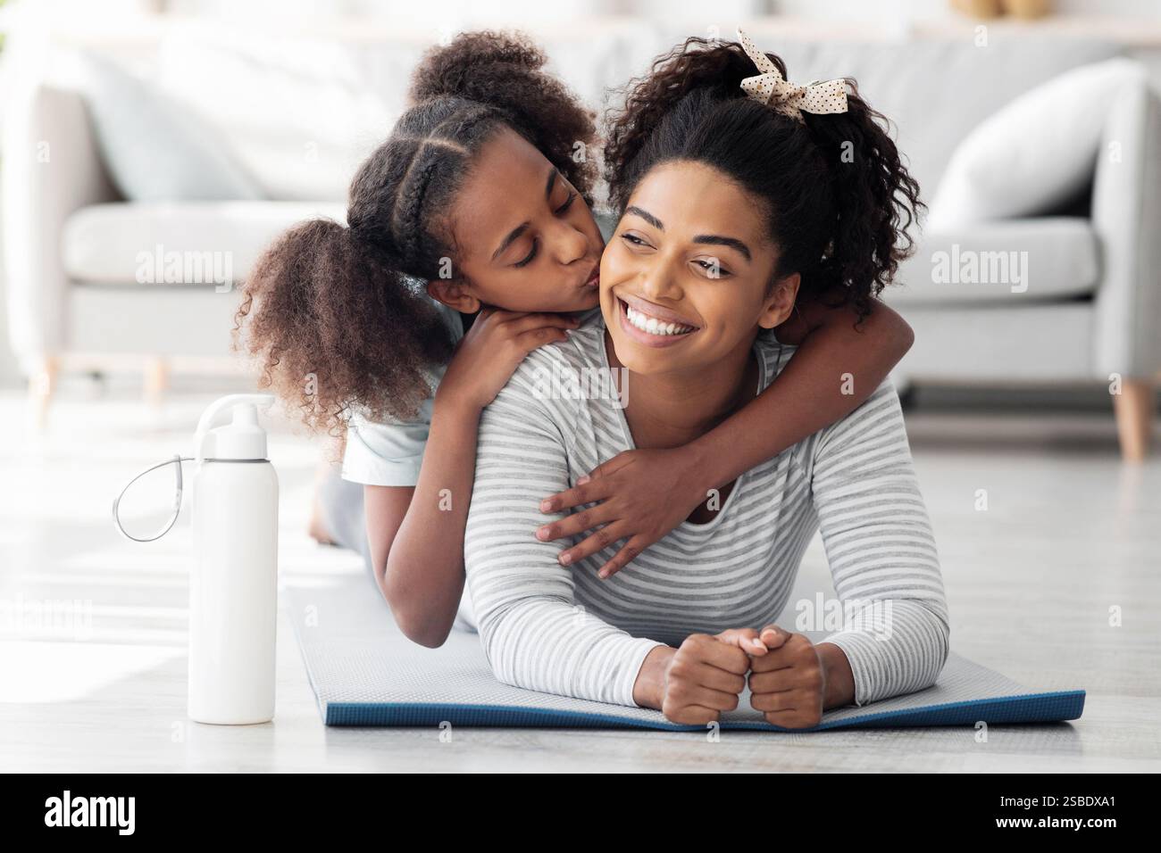 Buona madre nera e figlia coccolarsi mentre praticano lo yoga Foto Stock