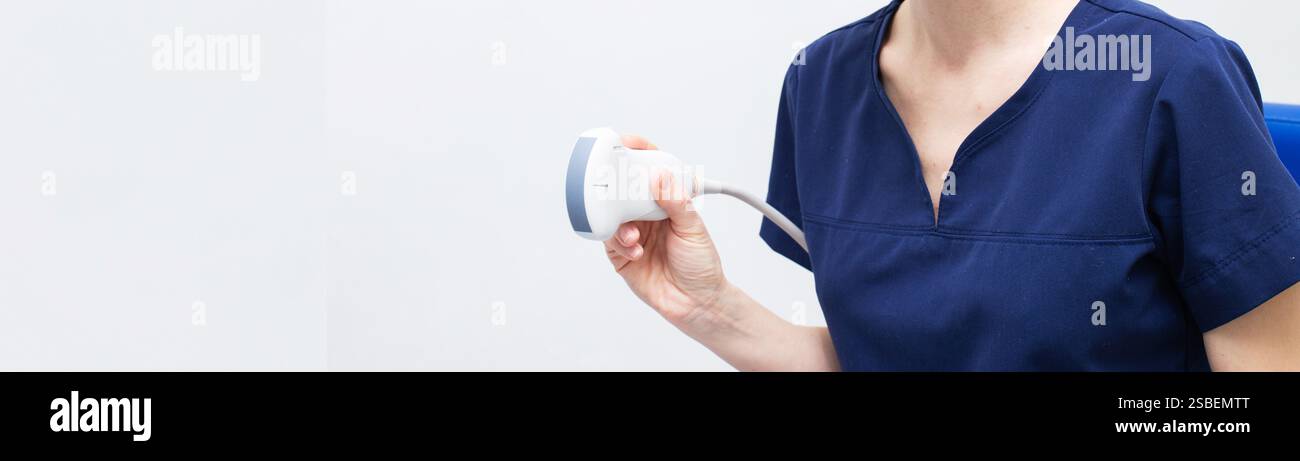 Donna medico in uniforme seduta in ufficio in un ospedale con apparecchiatura diagnostica a ultrasuoni e pronto per esaminare i pazienti e fare ultra Foto Stock