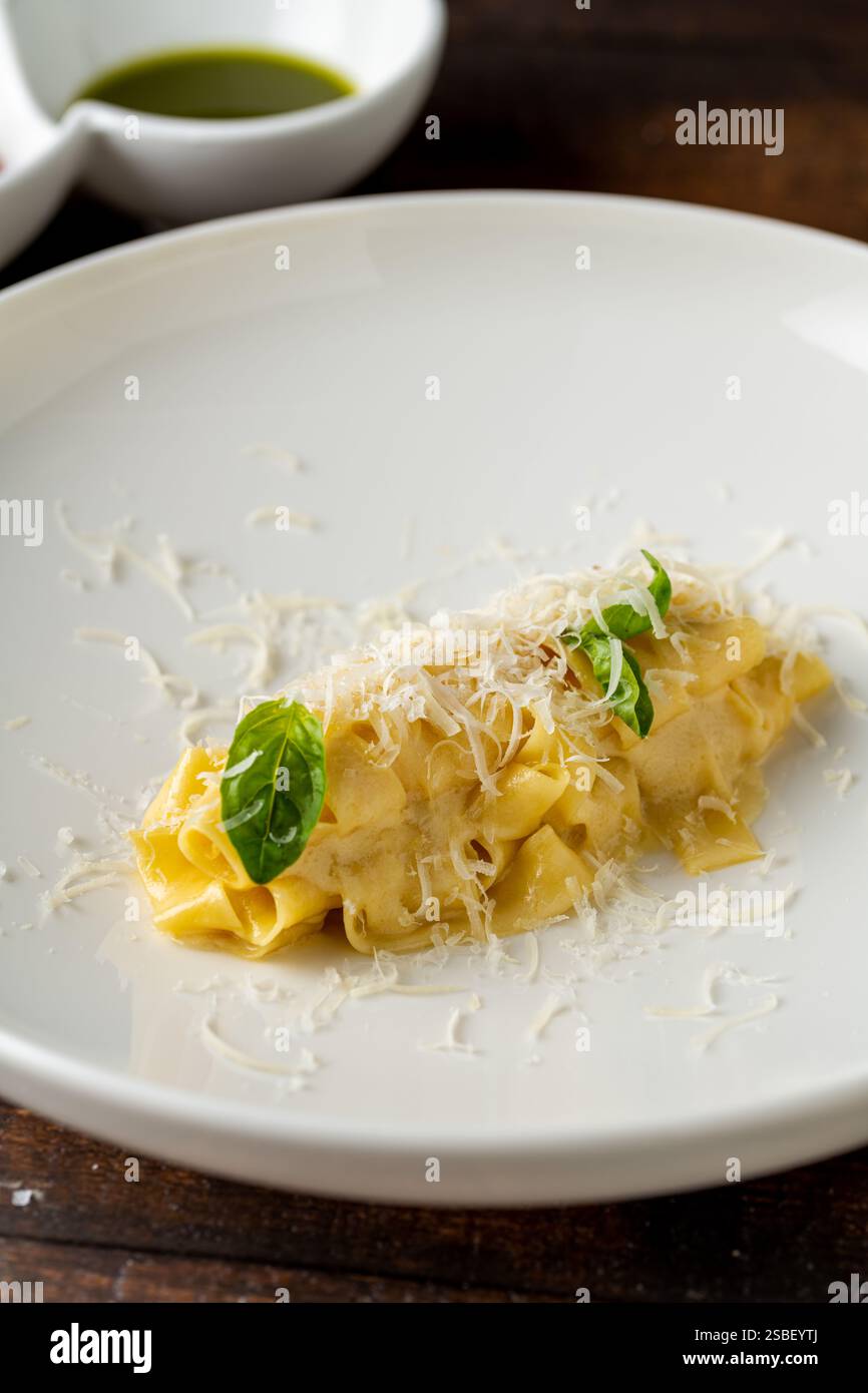 Deliziosa pappardelle di pasta italiana con parmigiano in porcellana bianca su un tavolo di legno Foto Stock