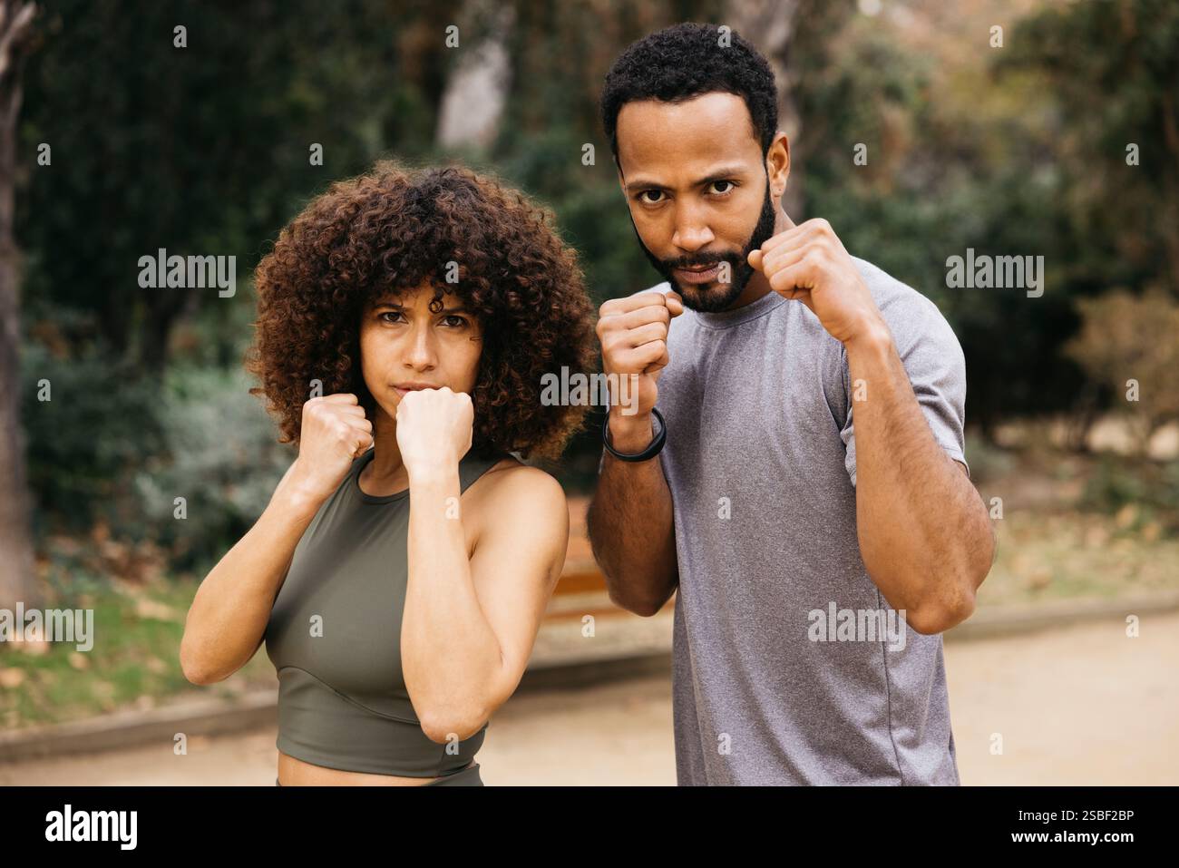 Un uomo e una donna che dimostrano autodifesa si muovono all'aperto, mostrando fitness, concentrazione e determinazione Foto Stock