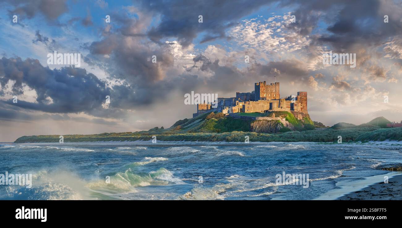 Foto dello storico castello medievale di Banburgh e della spiaggia con mare e onde sulla costa nord-orientale del Northumberland in Inghilterra, Regno Unito. Foto Stock
