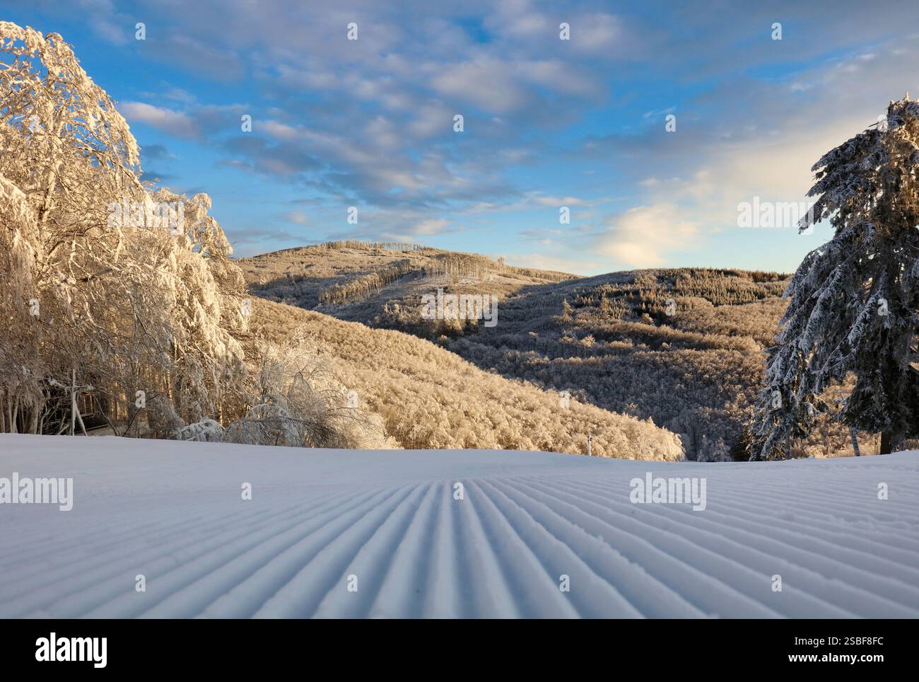 Nevicata appena preparata sulla pista da sci della stazione sciistica in una soleggiata giornata invernale Foto Stock