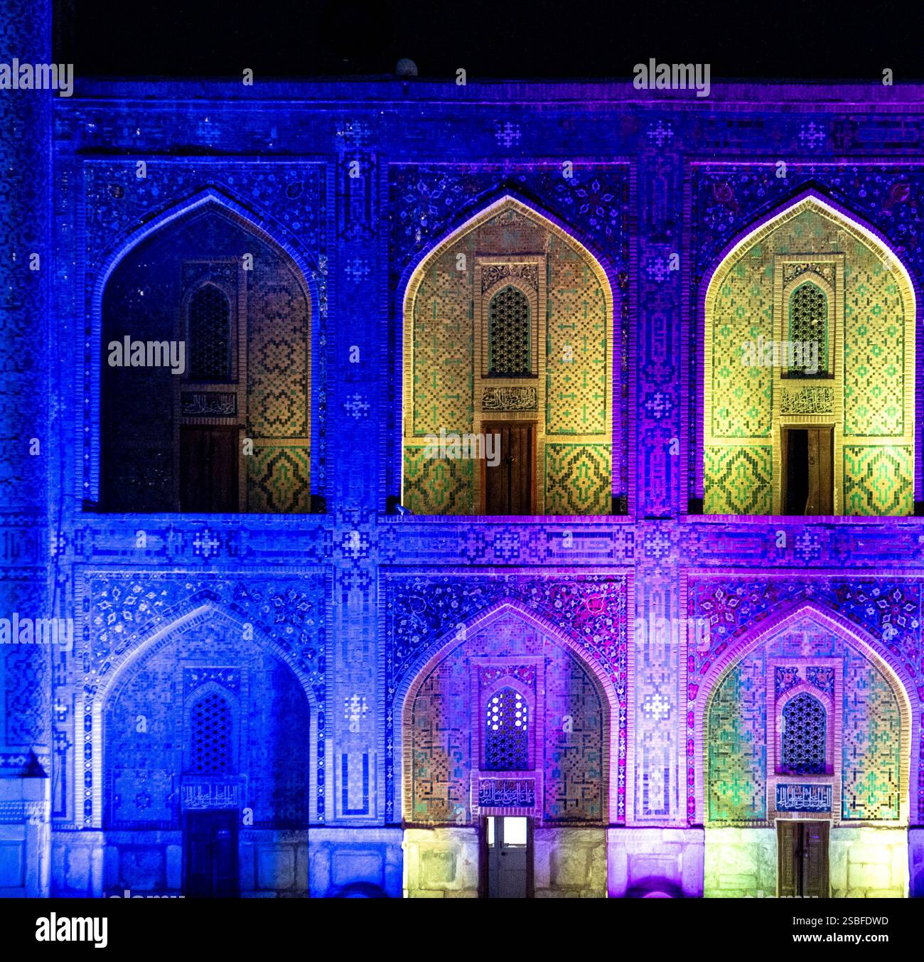 Un edificio storico splendidamente illuminato di notte, che mostra intricati lavori di piastrelle e finestre ad arco. La facciata è illuminata da vibranti sfumature di blu Foto Stock