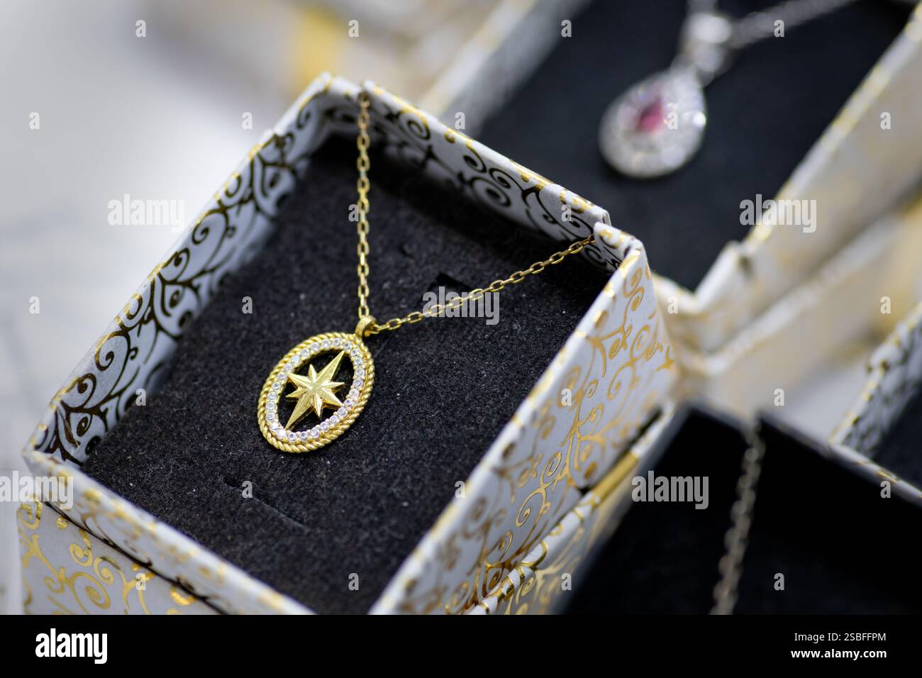 Una collana con pendente a forma di stella dorata con una montatura scintillante, esposta in un elegante portagioie, pronta da indossare Foto Stock