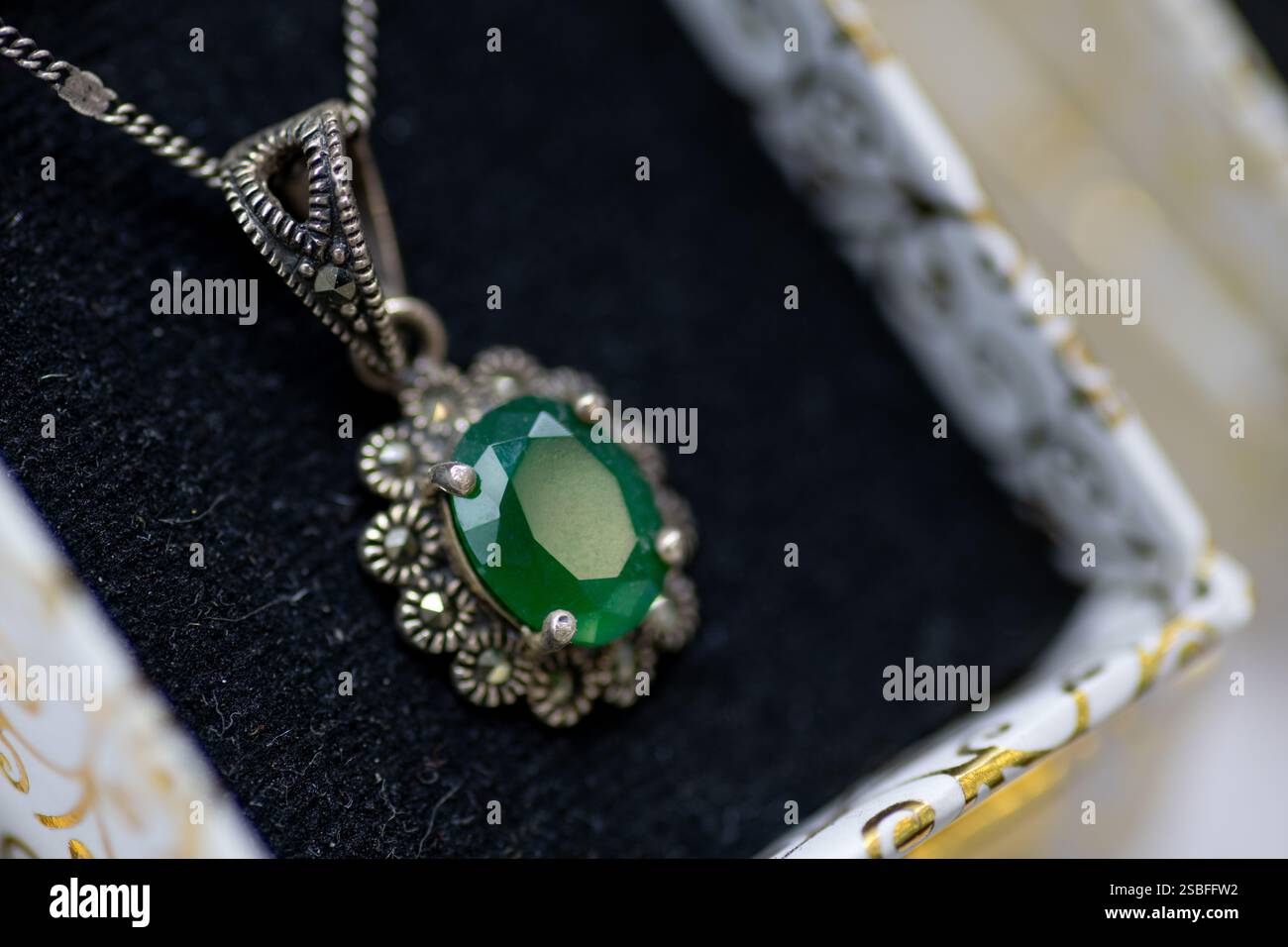 Un bellissimo primo piano di una collana verde con pendente in pietra preziosa con un'ambientazione in argento vintage, che mette in risalto l'intricata maestria artigianale Foto Stock