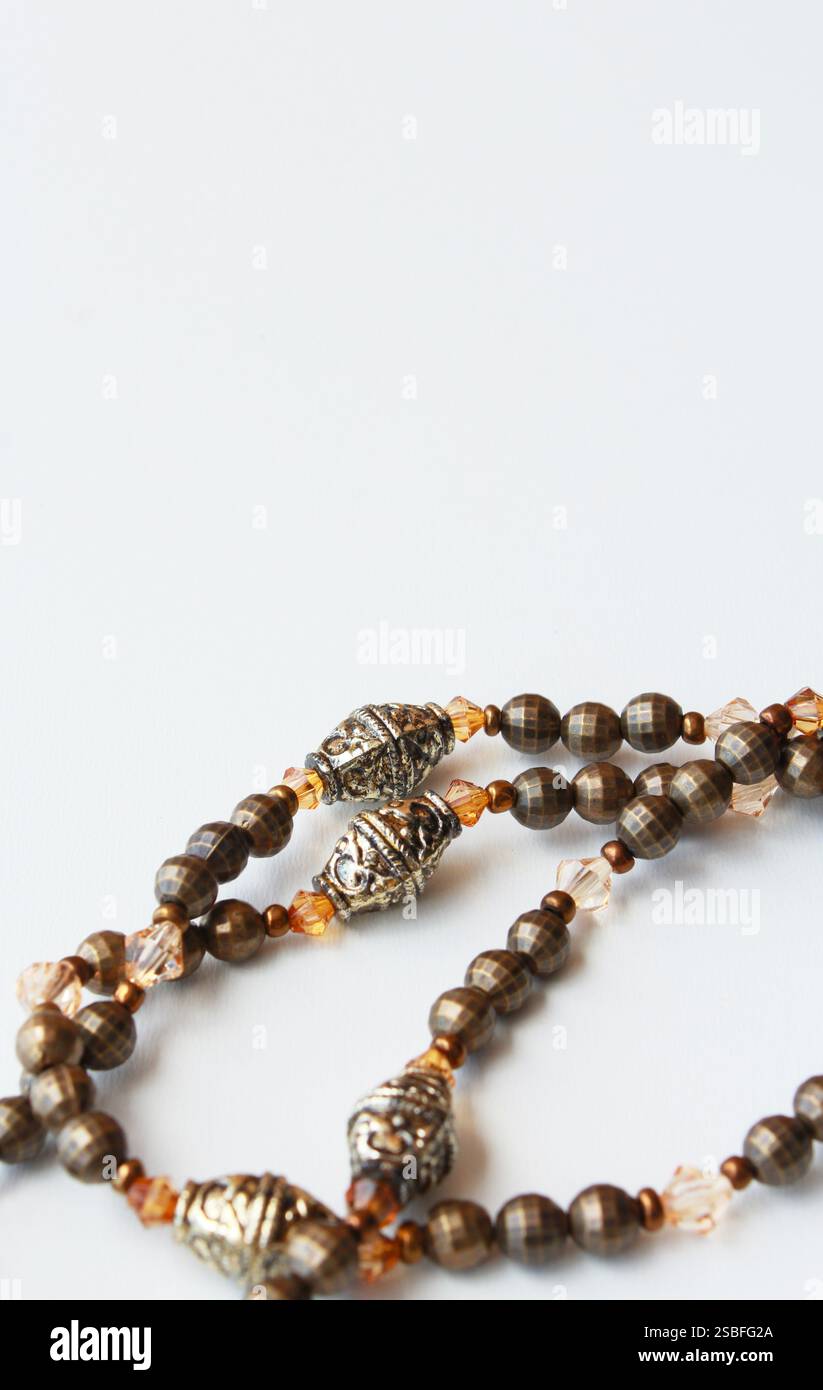 Elegante collana realizzata a mano in perline marrone e bronzo in stile vintage. Bijoux sofisticato primo piano su sfondo bianco con spazio di copia. Foto Stock