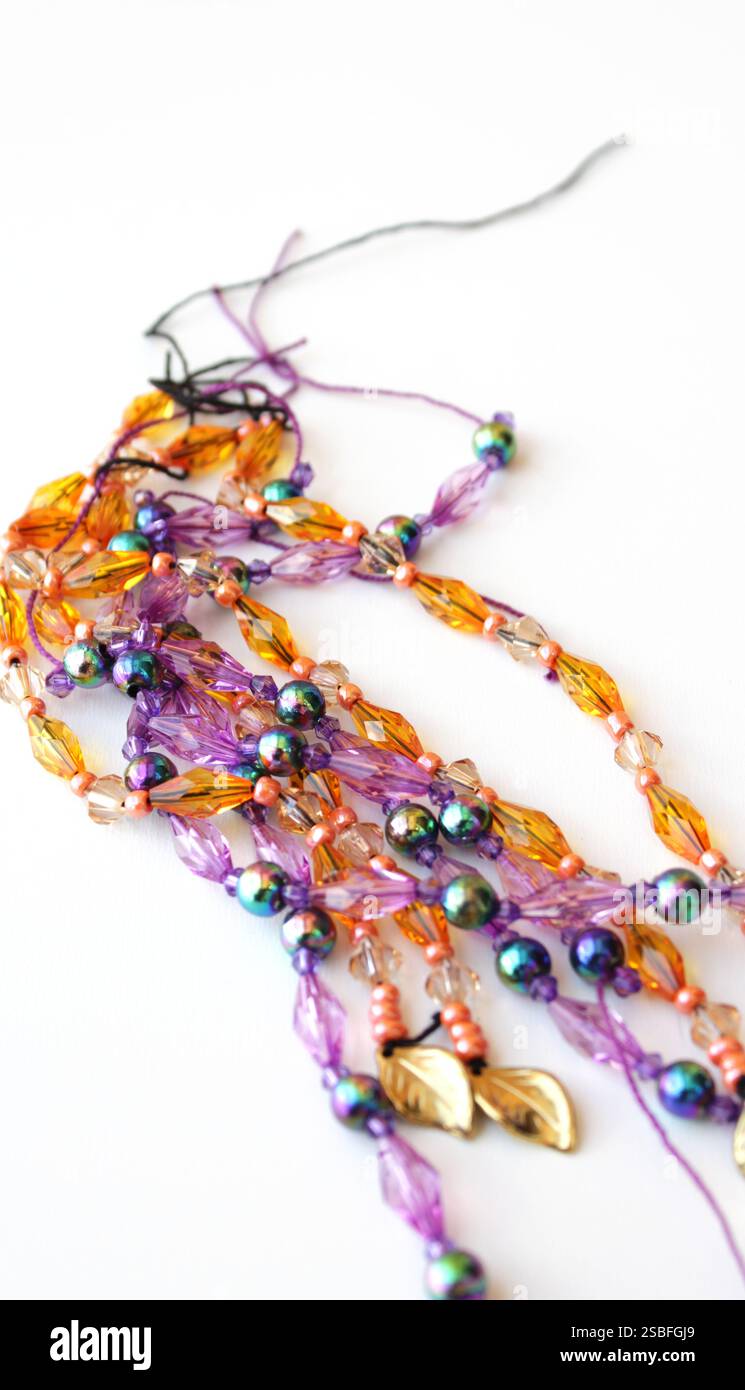 Filamenti di colorate perle acriliche per decorazioni e costumi del Carnevale brasiliano. Cordoncini con bordatura di colore viola e arancione. Foto Stock Filamenti di colorate perle acriliche per decorazioni e costumi del Carnevale brasiliano. Cordoncini con bordatura di colore viola e arancione. Foto Stock