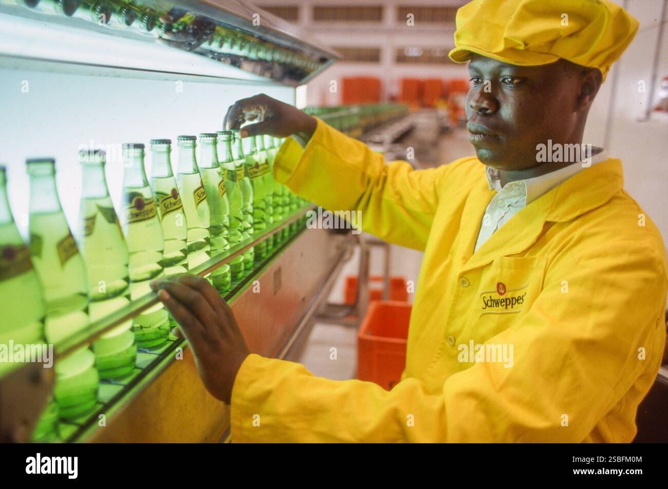 Kenya, Nairobi, Schweppes produce bevande analcoliche per il mercato locale. In fabbrica, le bottiglie di bibite analcoliche vengono controllate per assicurarsi che siano riempite Foto Stock