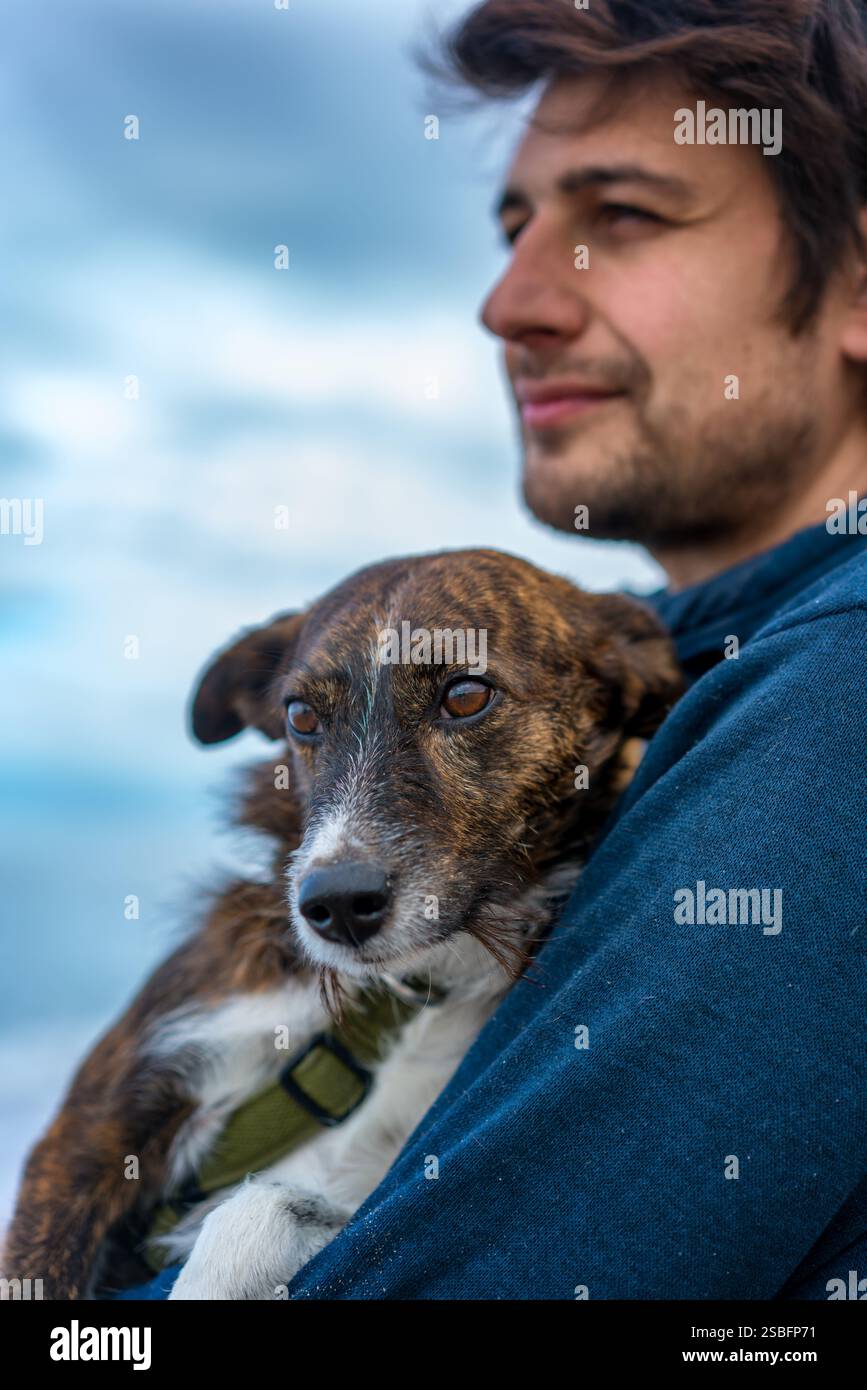 Uomo che tiene in grembo un bel cane marrone Foto Stock