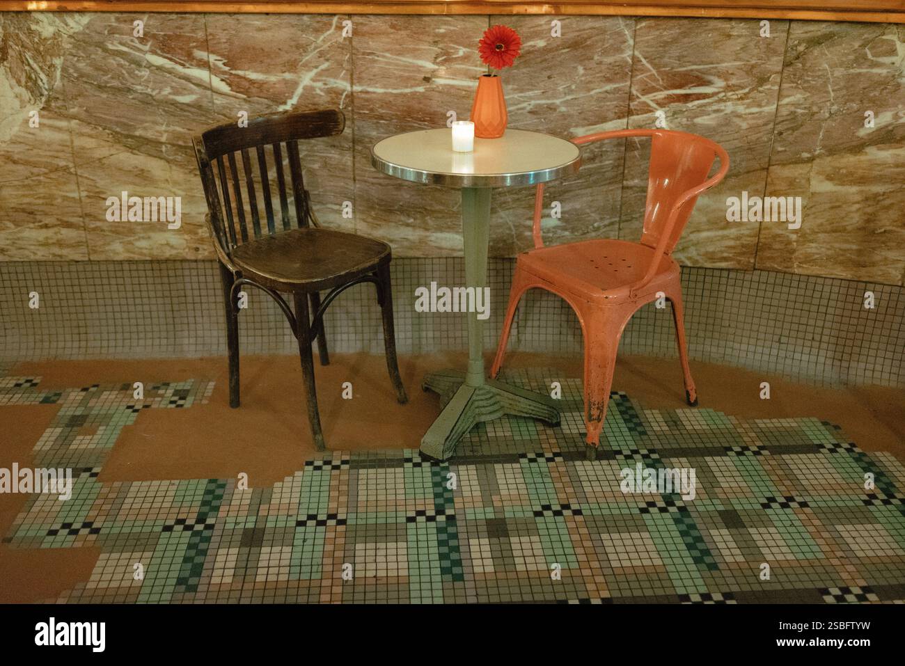 Ambientazione vintage cafÃ© con sedie abbinate e un unico fiore. Foto Stock