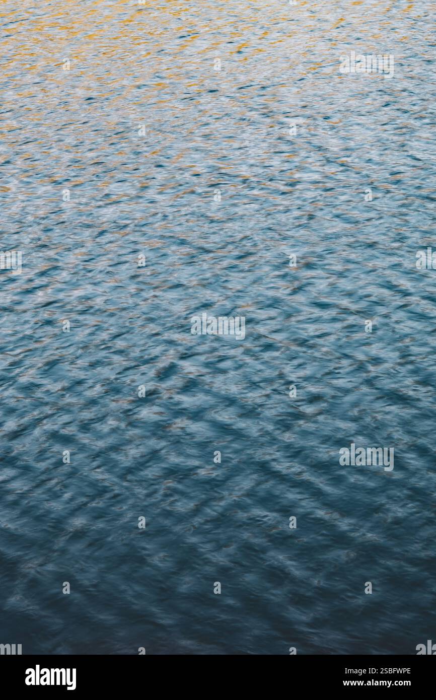 Riflessioni dorate sull'acqua increspata al tramonto Foto Stock
