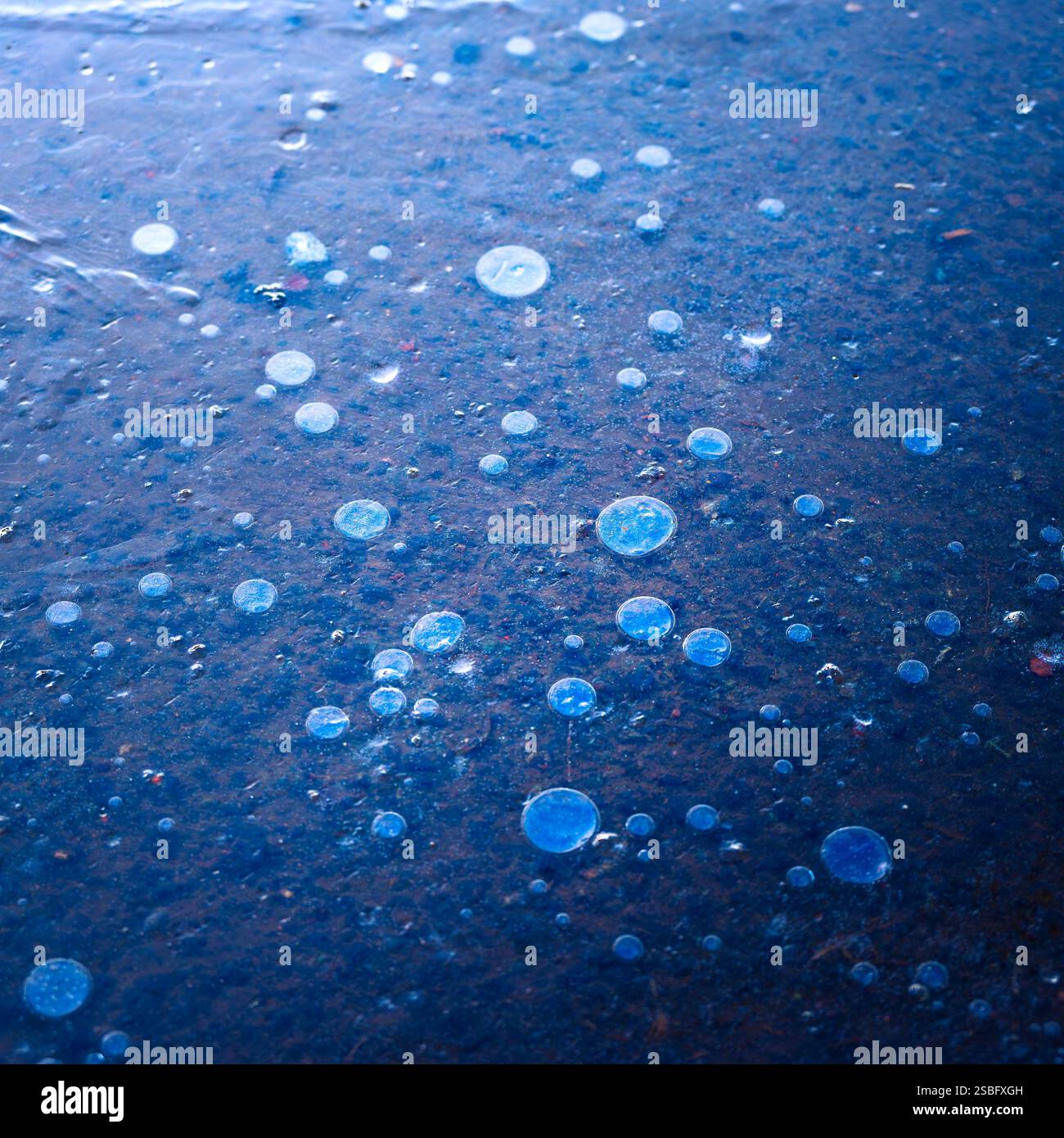 Immagine astratta della consistenza di bolle intrappolate sotto un foglio di ghiaccio su una strada gelida la mattina in inverno Foto Stock