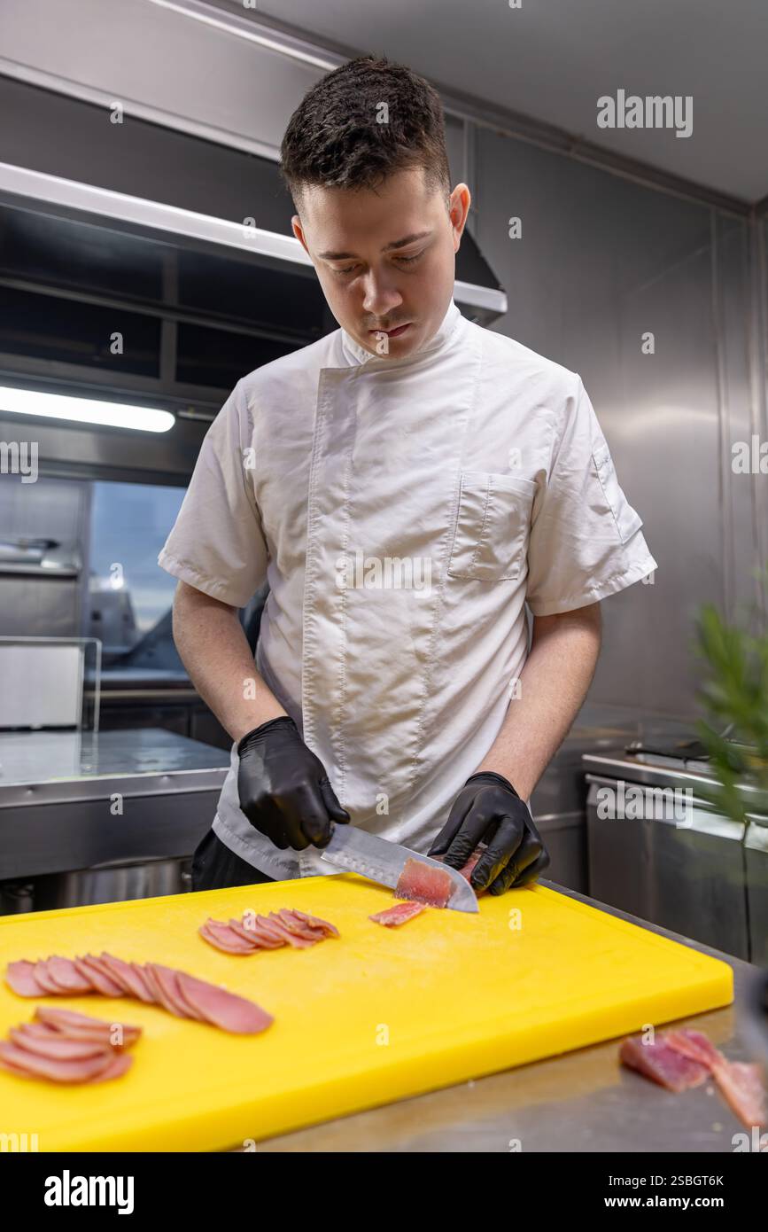Chef professionista affettare tonno su tagliere giallo nella cucina del ristorante Foto Stock
