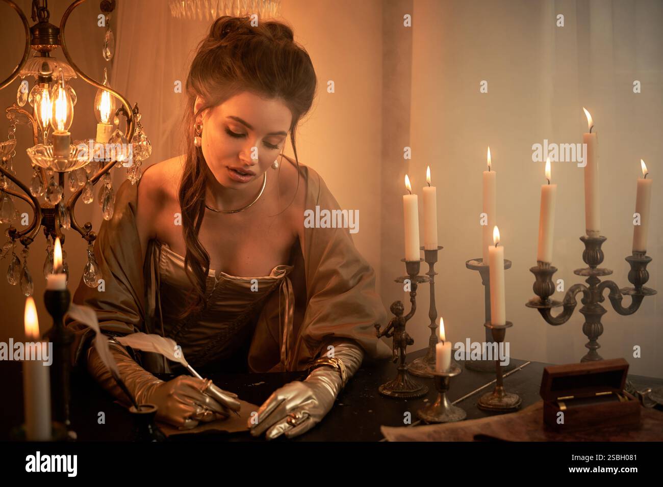 Una giovane donna in costume da vampiro scrive con attenzione a lume di candela, avvolta nel mistero. Foto Stock