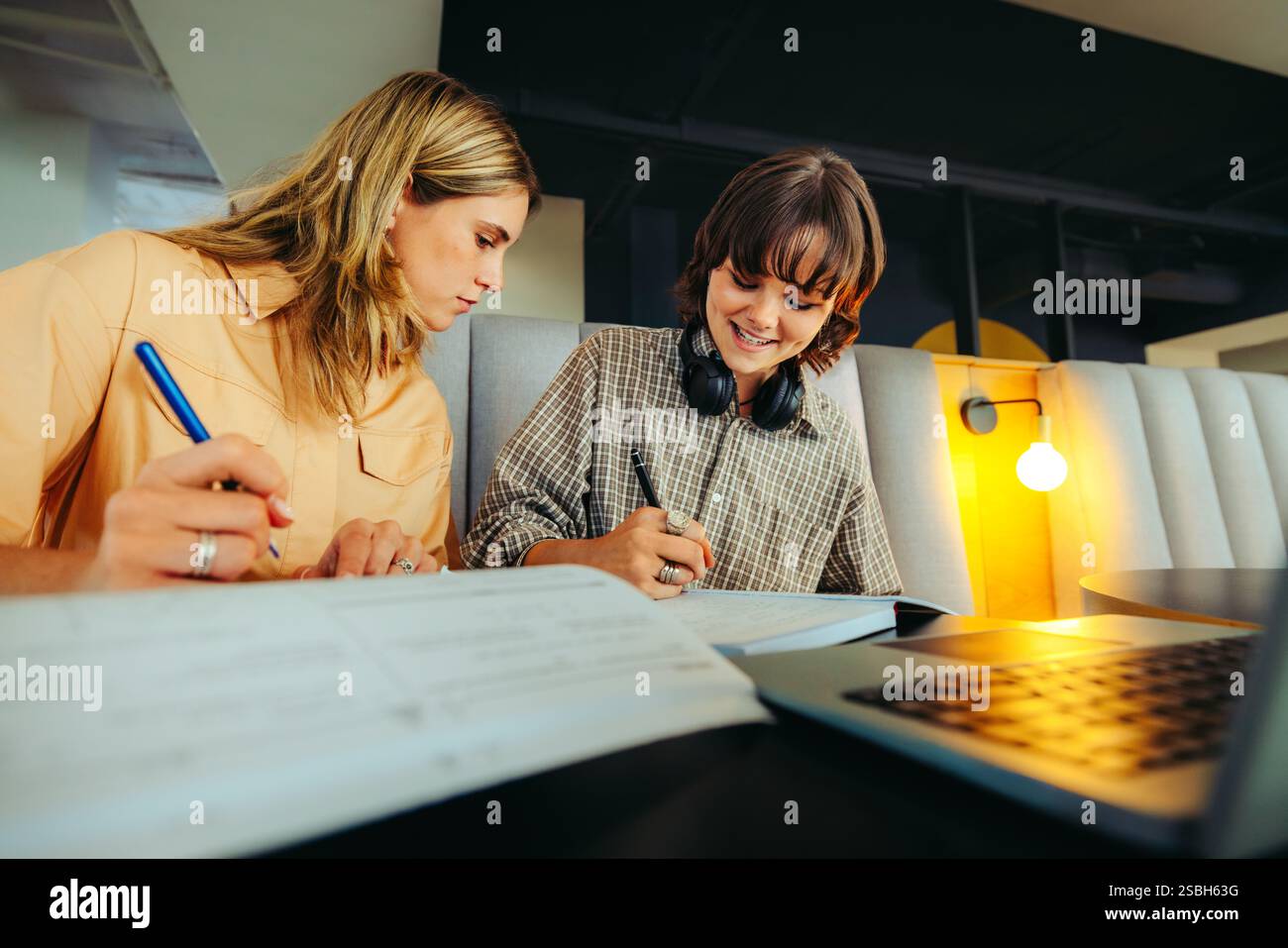 Studenti adolescenti che lavorano insieme sui compiti scolastici, condividono idee in un ambiente di studio contemporaneo. L'apprendimento mirato e la collaborazione sono fondamentali Foto Stock
