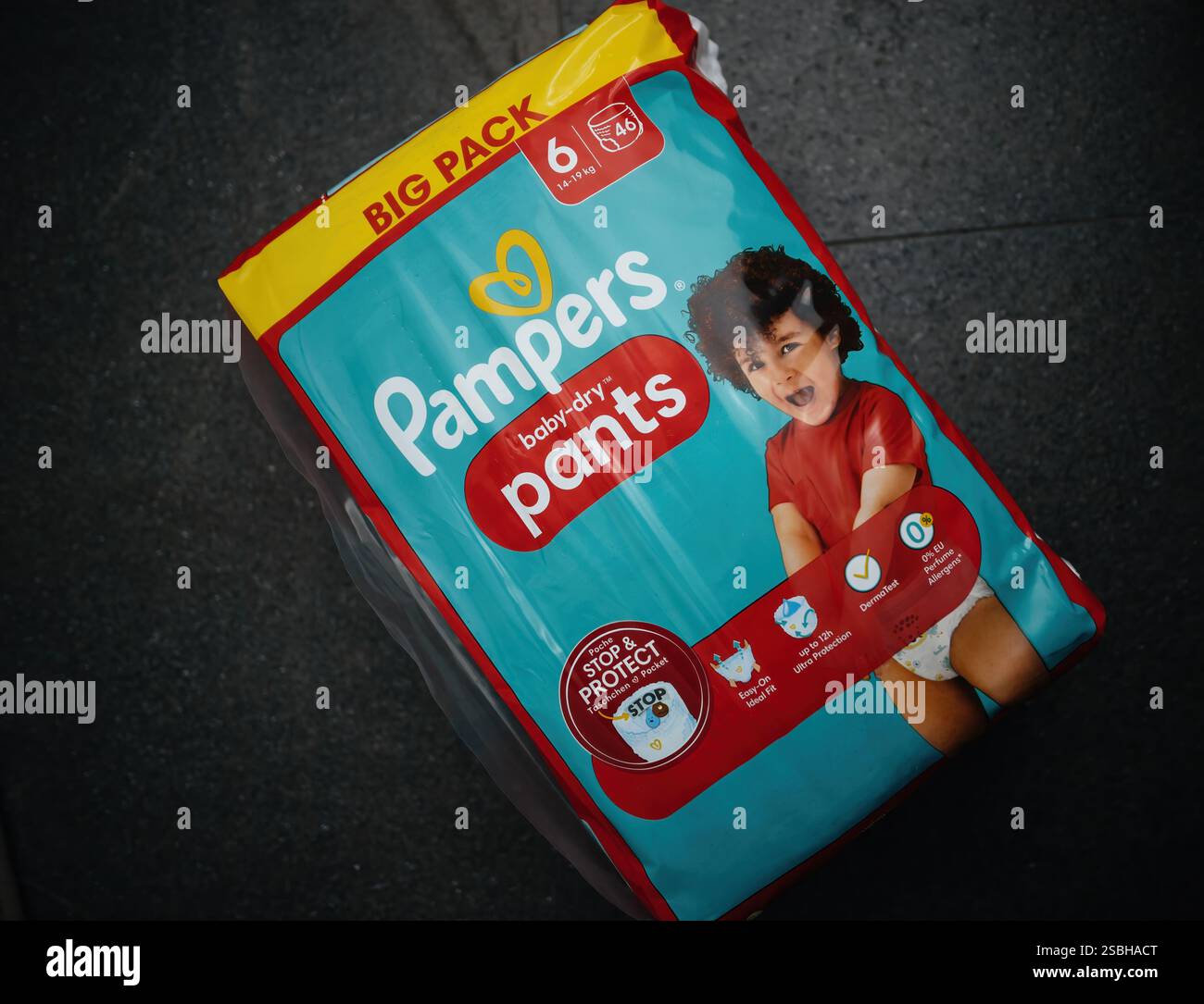 Parigi, Francia - 18 marzo 2023: Un pacchetto di pantaloni Pampers Baby-Dry della taglia 6, progettati per essere indossati e comodi, con un bambino sorridente sulla baia Foto Stock