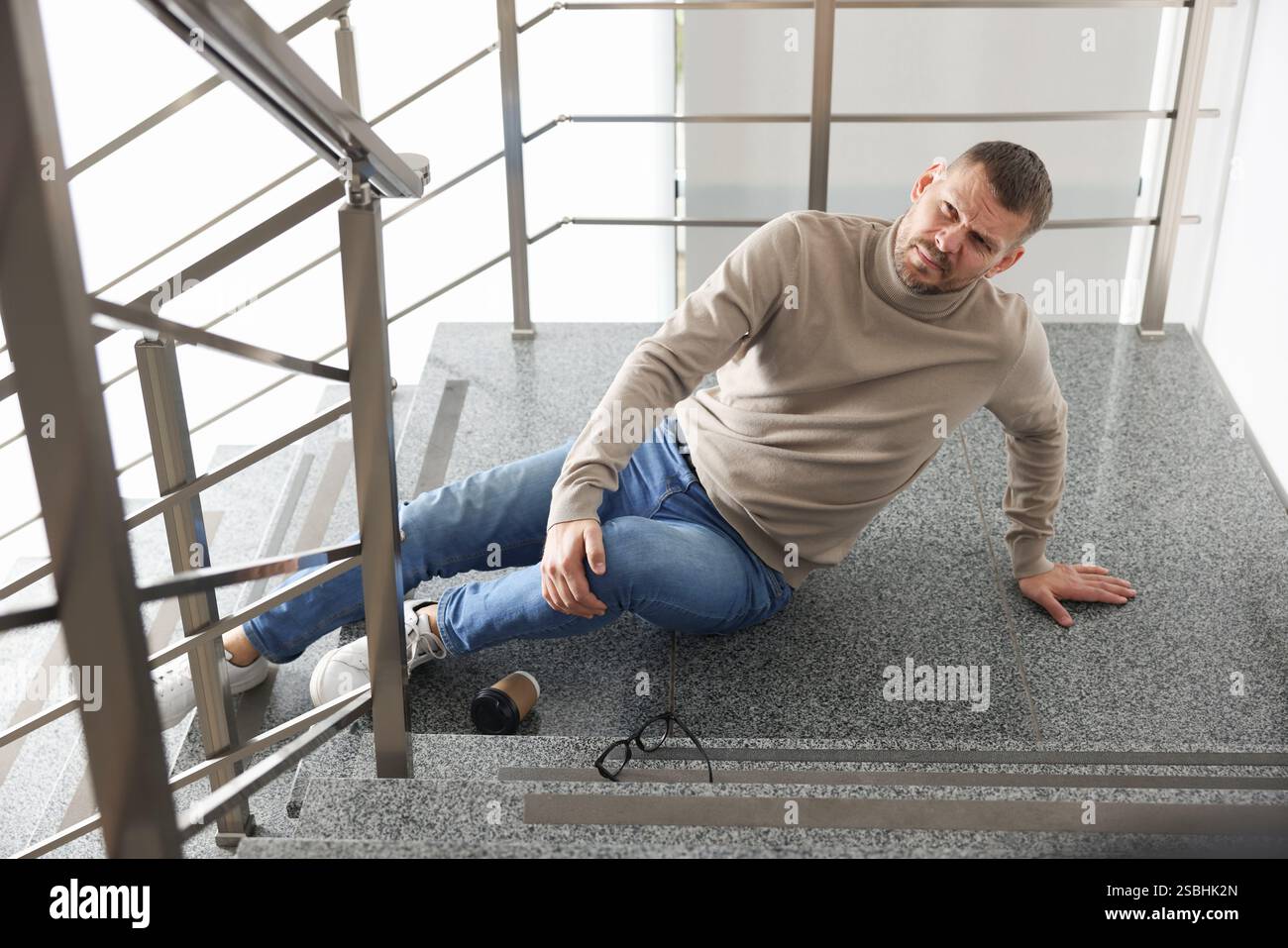 Uomo ferito sulle scale dell'edificio dopo la caduta. Incidente pericoloso Foto Stock