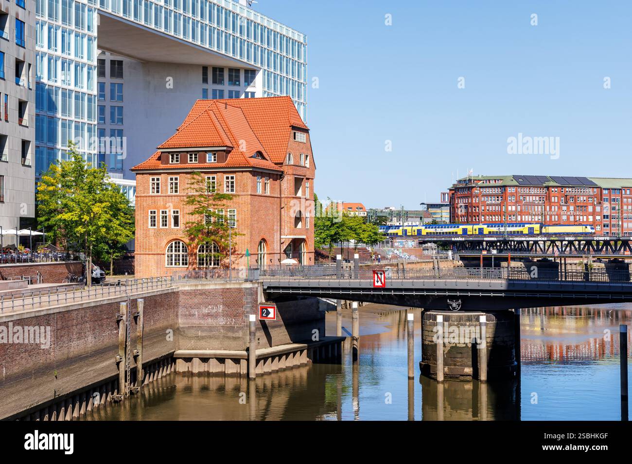 Amburgo, Germania - 12 agosto 2024: Treno regionale Metronom trasporto pubblico sul ponte Oberhafen con Altes Zollhaus ad Amburgo, Germania. Foto Stock