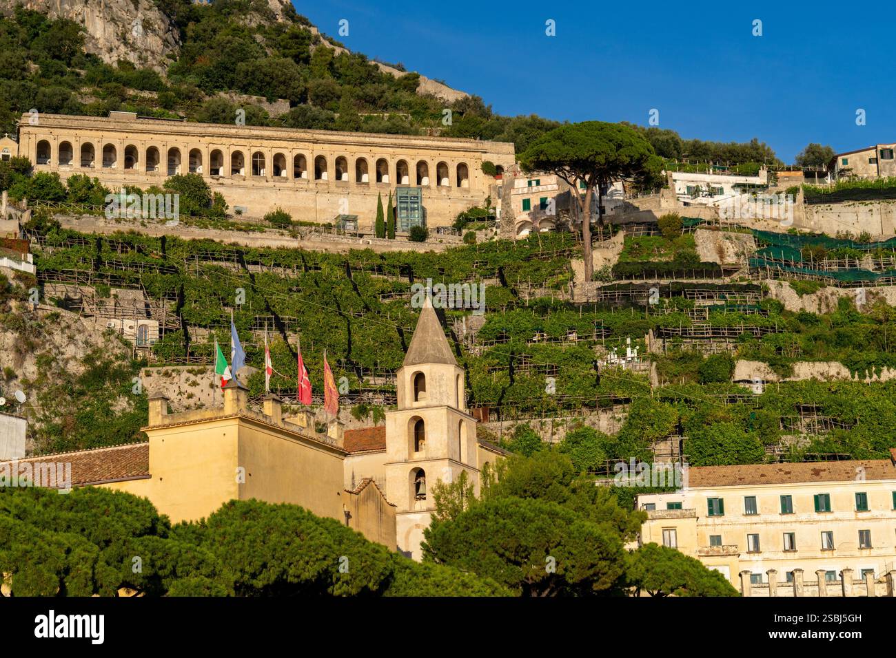 Campanile del municipio e vigneti e frutteti terrazzati nella città di Amalfi, sulla Costiera Amalfitana. Il Cimitero Monumentale è in cima. Foto Stock