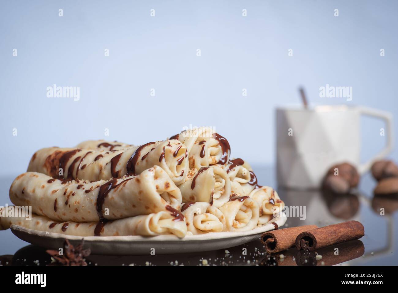 Le crepe arrotolate condite con ricco cioccolato e ornate con spezie mostrano una deliziosa miscela di sapori, creando una combinazione perfetta per il dessert Foto Stock