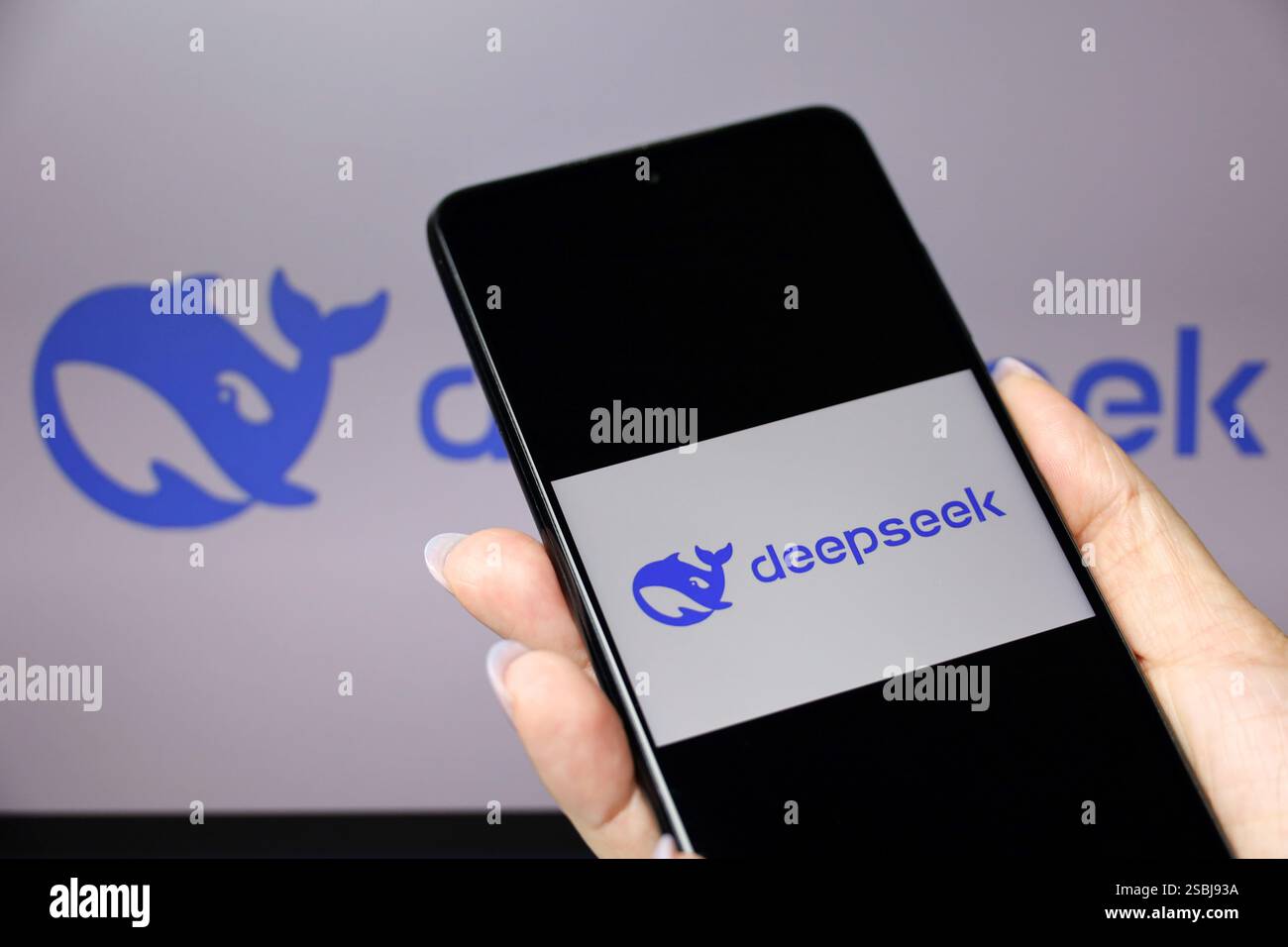 Logo DeepSeek ai sullo schermo dello smartphone in un display femminile per mano e computer Foto Stock