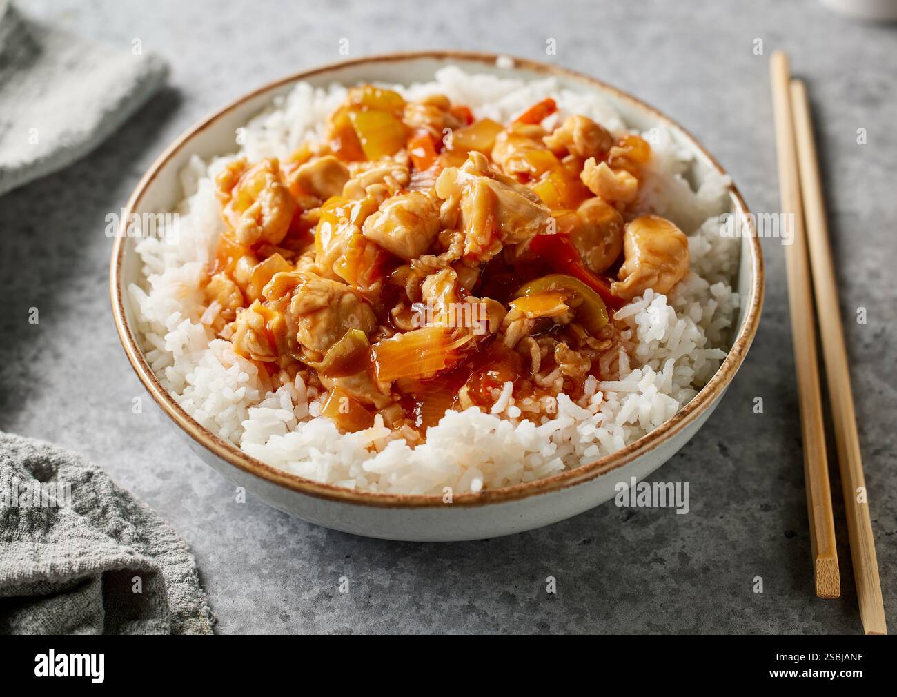 ciotola di riso bollito con salsa agrodolce di pollo sul tavolo da cucina grigio Foto Stock