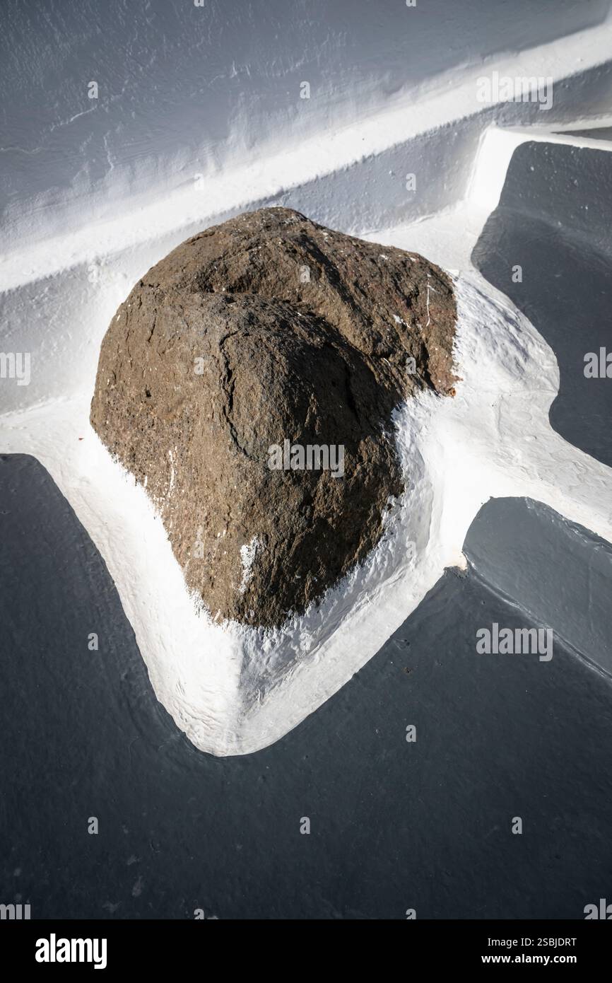 Roccia vulcanica incorniciata da vernice bianca e grigia in fondo a una scala sulle scogliere di Santorini, Grecia Foto Stock