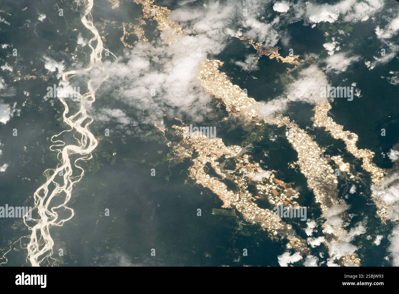 Immagine satellitare di pozzi di prospezione dell'oro e deforestazione nello stato di madre de Dios nell'Amazzonia peruviana orientale. A sinistra si vedono i canali serpeggianti del fiume Inambari. Immagine acquisita dalla stazione spaziale Internazionale il 24 dicembre 2020. Foto Stock