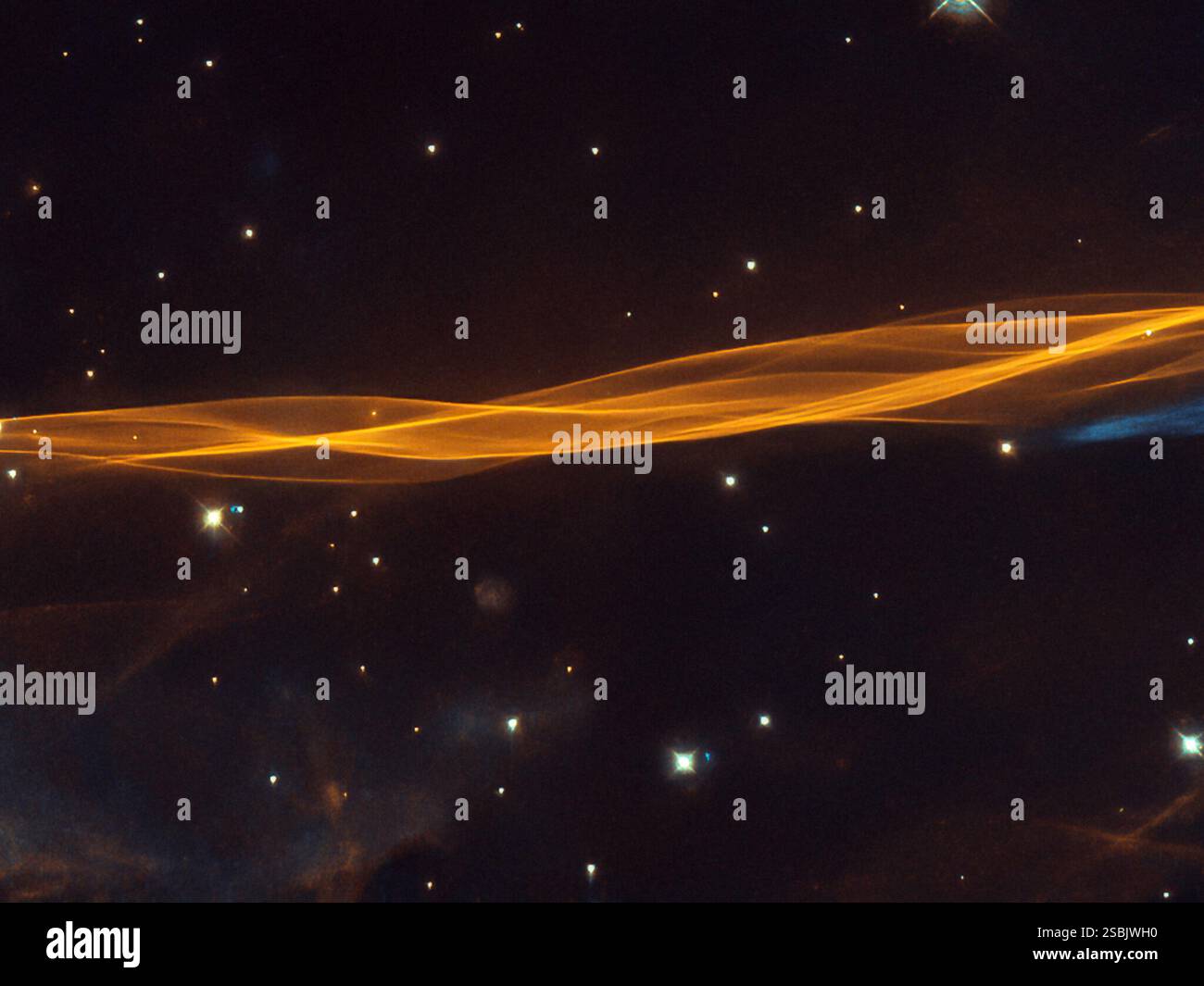 Questa immagine del telescopio spaziale Hubble raffigura una piccola sezione dell'onda d'esplosione della supernova di Cygnus, situata a circa 2400 anni luce di distanza. Il residuo della supernova si trova nella costellazione di Cigno, dove copre un'area 36 volte più grande della luna piena. L'onda d'urto segna il bordo esterno del residuo della supernova e continua ad espandersi a circa 350 chilometri al secondo. L'interazione tra il materiale espulso e il materiale interstellare a bassa densità trascinato dall'onda d'urto forma la caratteristica struttura simile a quella di un velo visibile in questa immagine. Foto Stock