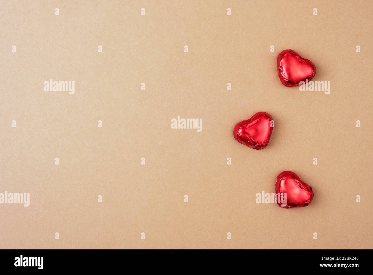 I cuori rossi caramelle su una superficie beige, simboleggiano l'amore e il romanticismo in una composizione minimalista ed elegante. Il giorno di San Valentino. Vista dall'alto, piatta Foto Stock
