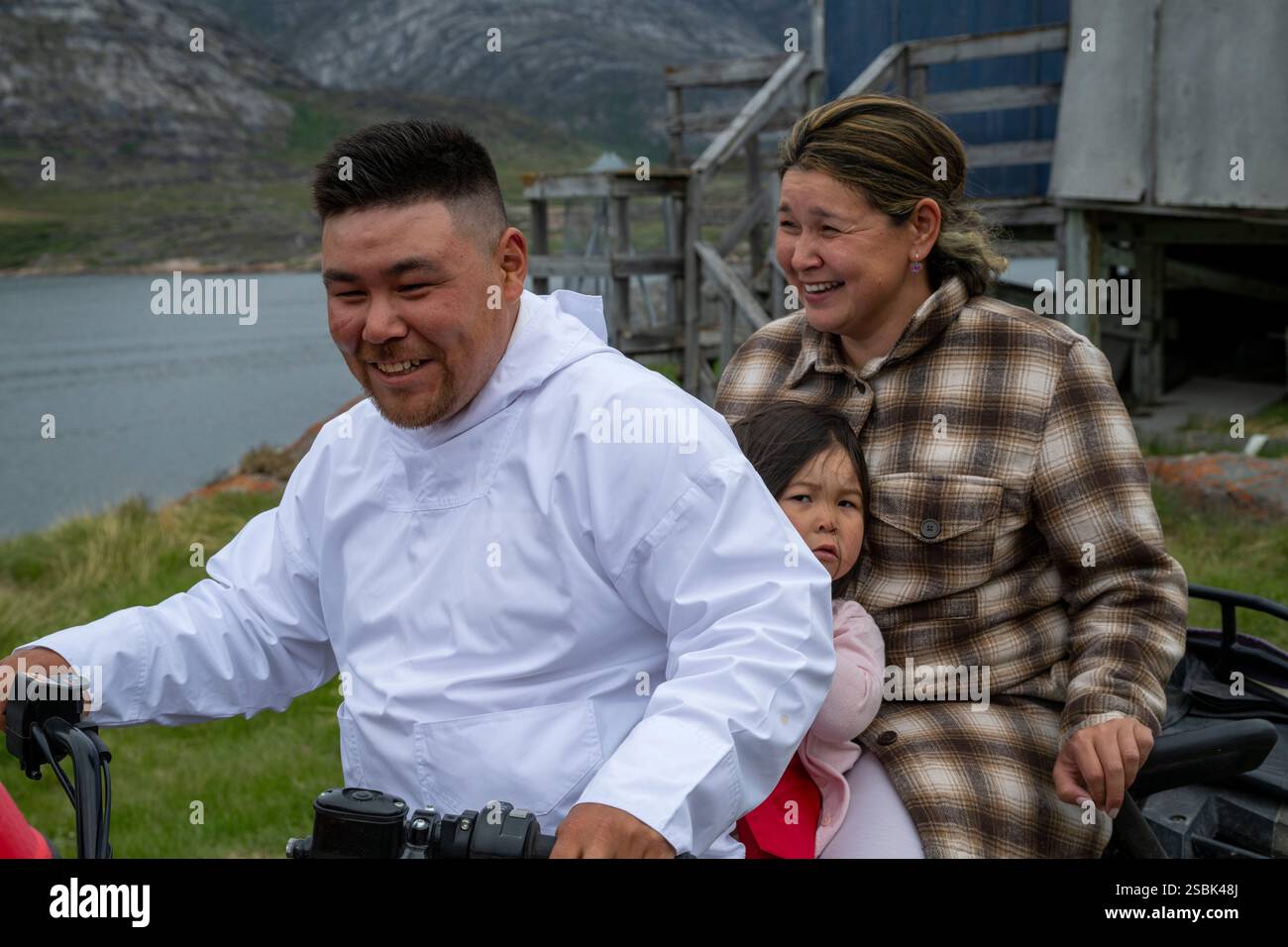 I membri della famiglia condividono un momento di gioia viaggiando insieme a bordo di un veicolo nel villaggio di Sarfannguit, un sito patrimonio dell'umanità dell'UNESCO in Groenlandia. Foto Stock