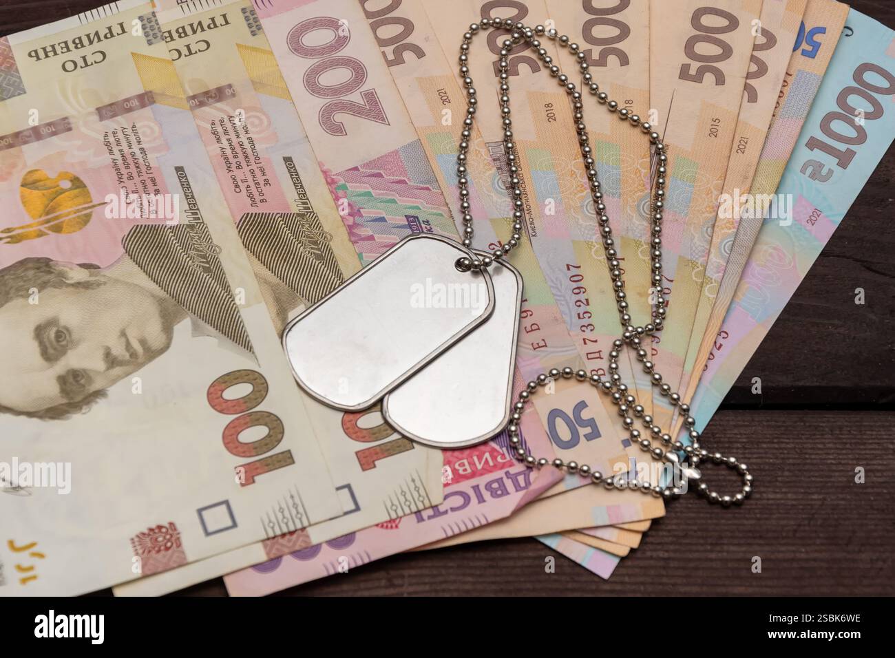 Gettone militare metallico sulle banconote ucraine - concetto di pagamenti militari e sostegno economico Foto Stock
