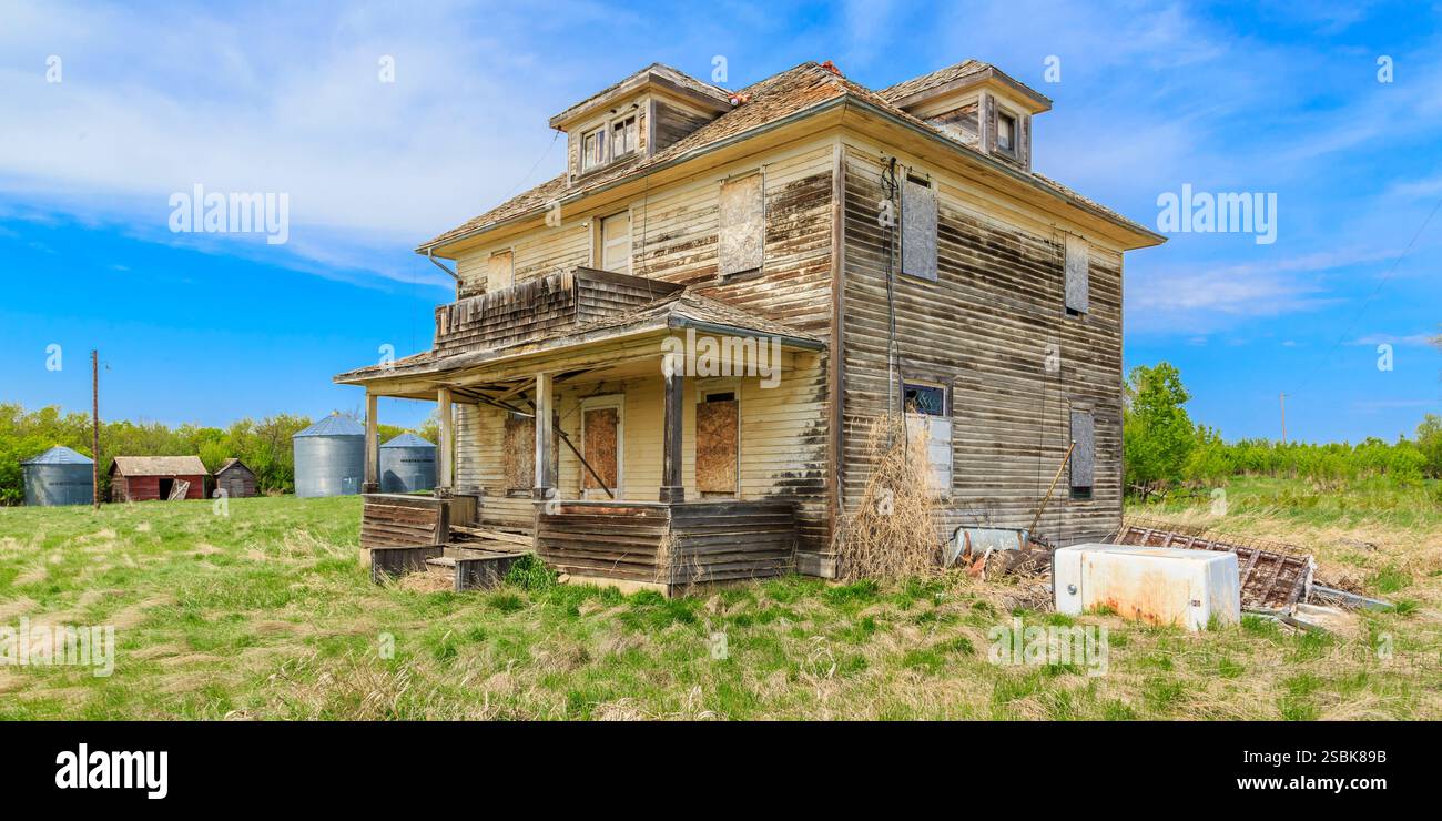 Casa grande e vecchia con un portico e molte finestre. La casa è circondata da un campo Foto Stock