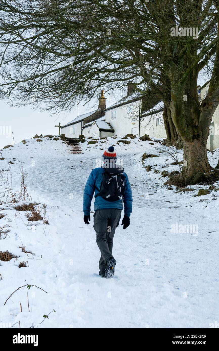 Uomo che cammina verso White Wells Bath House durante una passeggiata invernale, Ilkley Moor, Ilkley, West Yorkshire Foto Stock