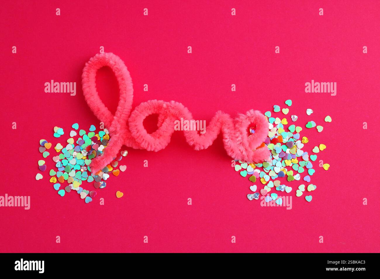 Parola d'amore con un gruppo di cuori colorati alle sue estremità Foto Stock