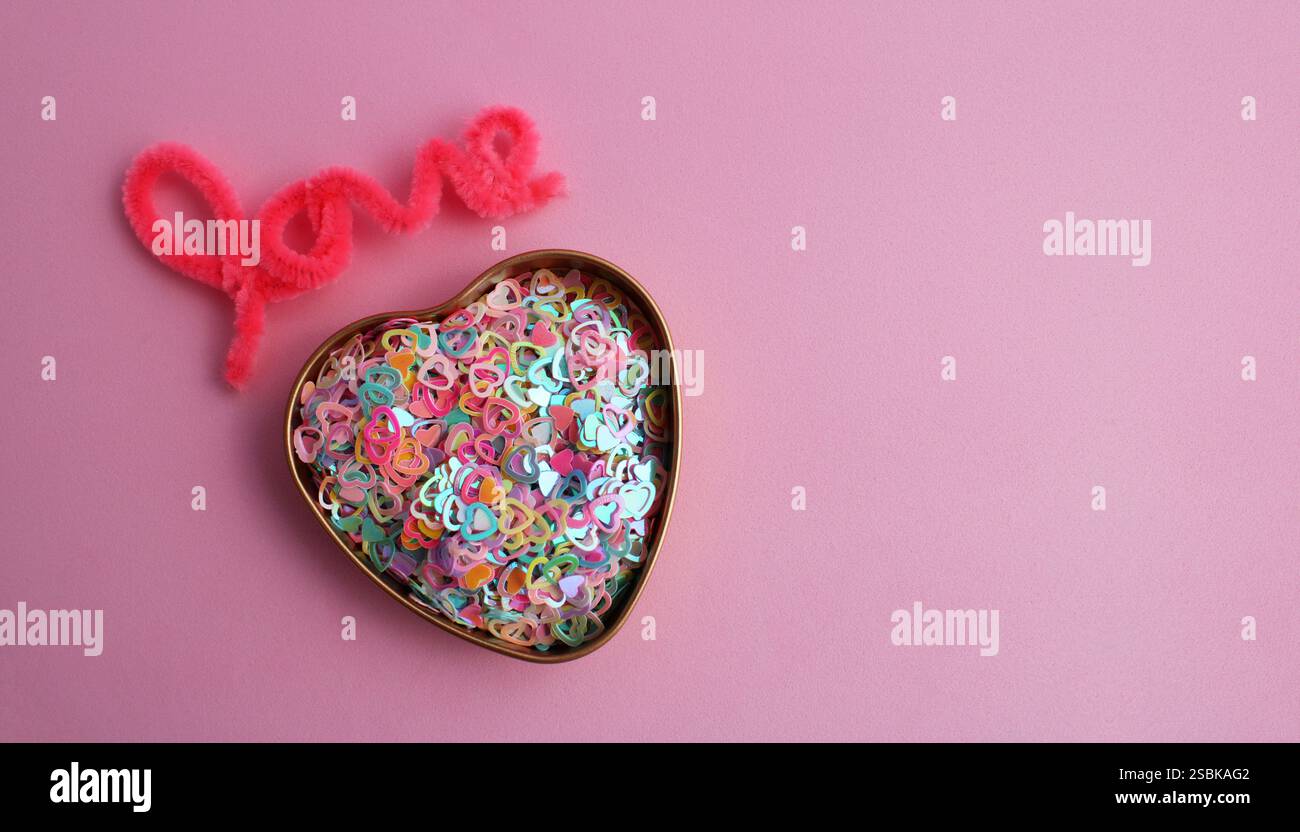 Contenitore pieno di cuori colorati accanto alla parola amore Foto Stock
