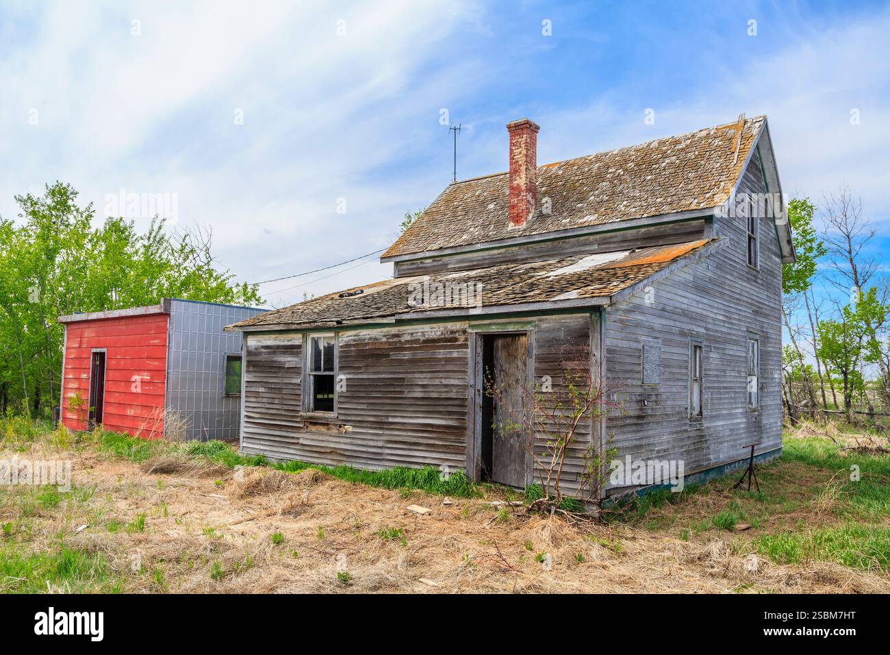 Casa rossa e bianca con un camino. La casa è vecchia e ha molta ruggine Foto Stock