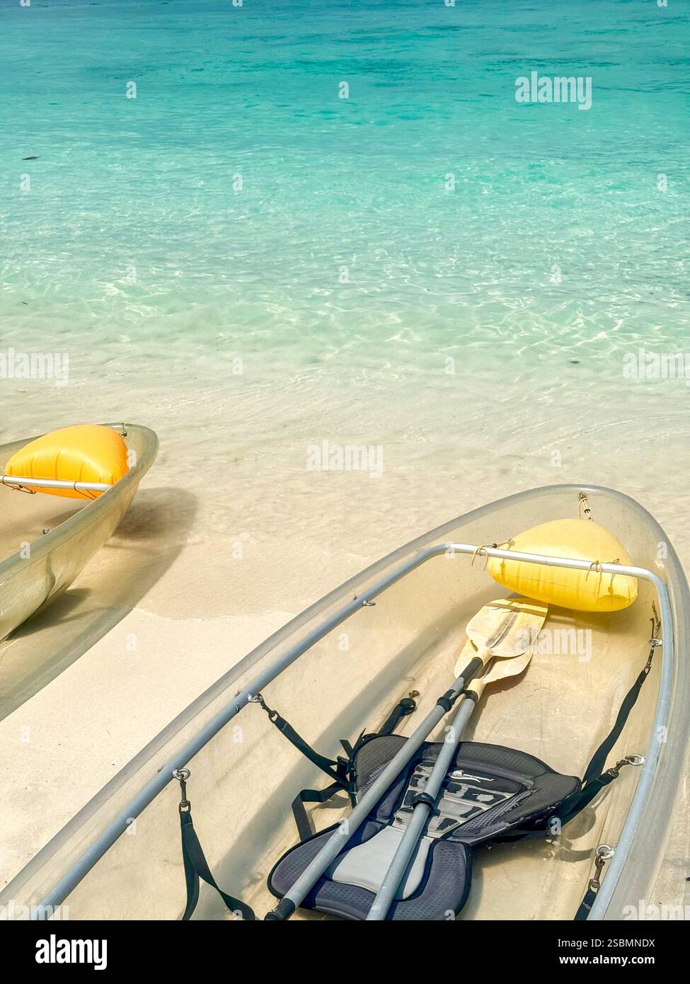 Kayak trasparenti su una spiaggia tropicale con acque turchesi Una tranquilla spiaggia tropicale con tre kayak trasparenti su soffice sabbia bianca, sopra - Immagine stock catturata con smartphone