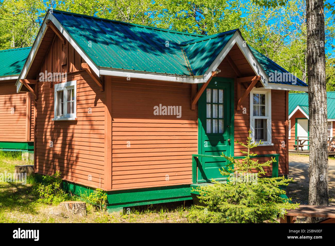 Piccola casa marrone con tetto verde. Il tetto è inclinato. La casa ha una porta verde Foto Stock