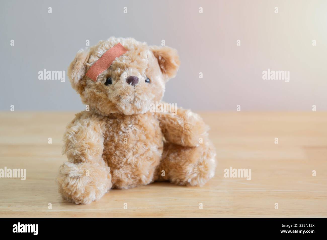 Orso Teddy è giocoso e ha avuto un incidente così ha applicato la testa medica e ferita usando la benda. Messa a fuoco selettiva. Foto Stock