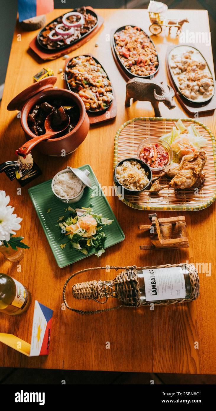 Un tavolo con una varietà di piatti e una bottiglia di Lambo. La scena è invitante e calda, come sembra un incontro di amici o familiari che condividono un pasto Foto Stock