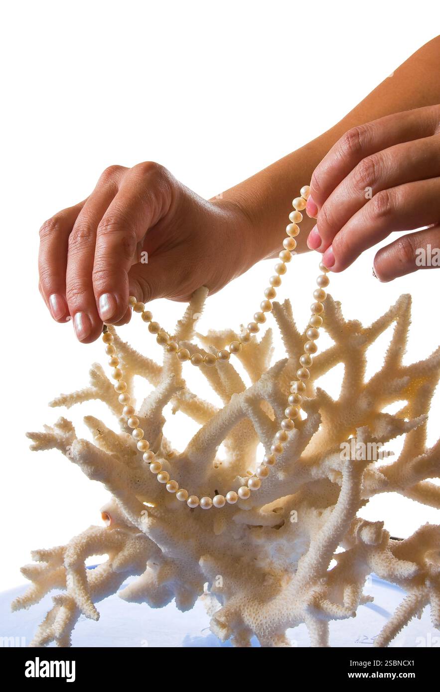 Una collana di perle nelle sue mani contro lo sfondo di corallo isolato su uno sfondo bianco Foto Stock