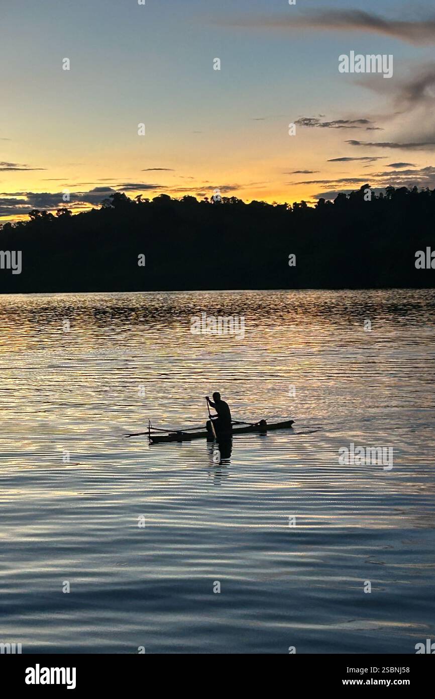 Residenti dell'isola di Tungelo nelle loro tradizionali canoe al tramonto, mare di Bismarck, provincia della nuova Irlanda, Papua nuova Guinea Foto Stock