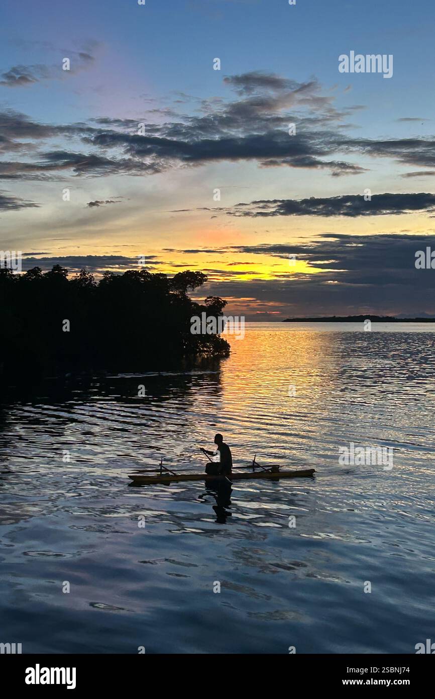 Residenti dell'isola di Tungelo nelle loro tradizionali canoe al tramonto, mare di Bismarck, provincia della nuova Irlanda, Papua nuova Guinea Foto Stock