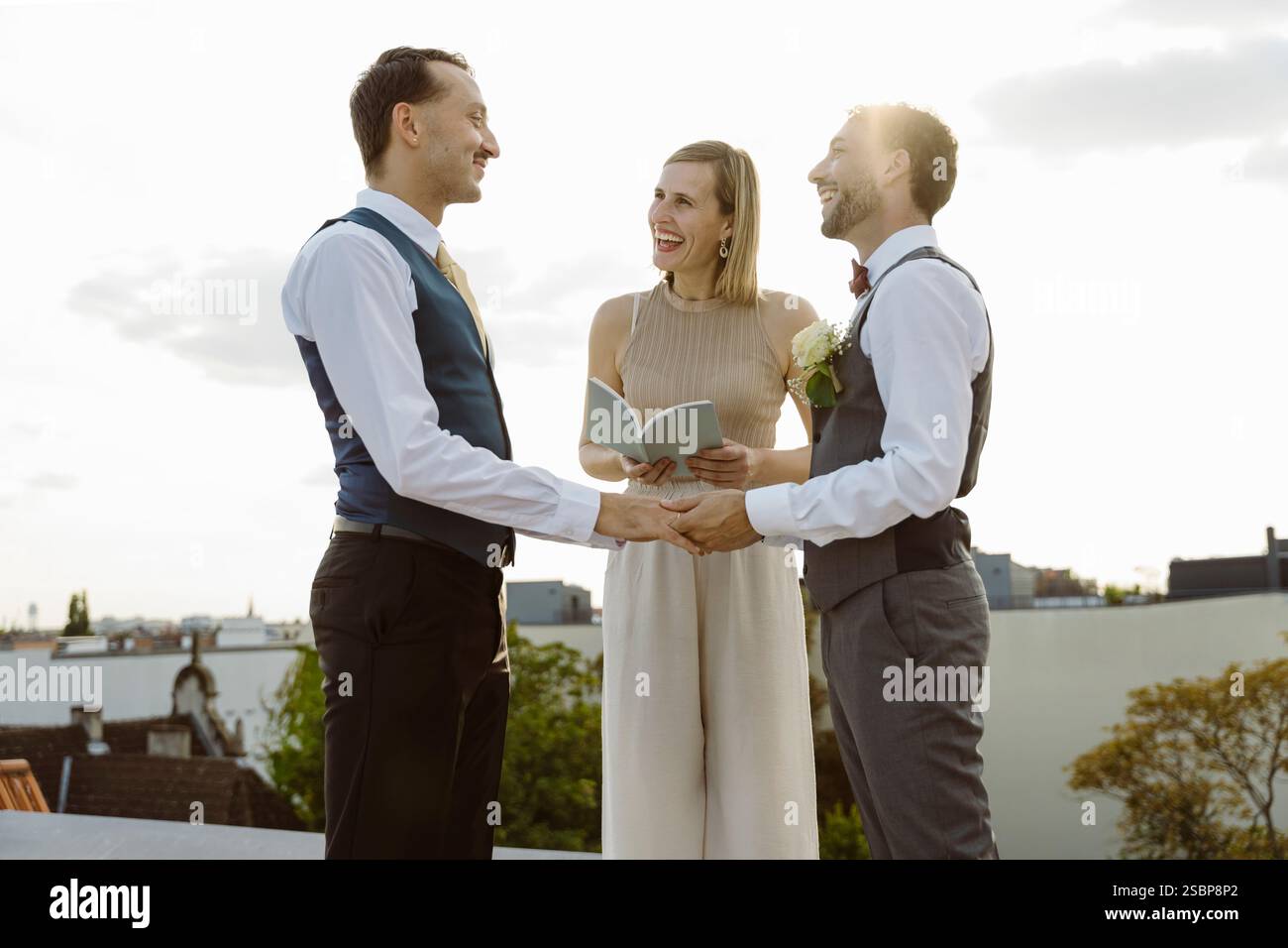 Felice ministro donna in piedi con una coppia gay che si tiene per mano durante la cerimonia nuziale Foto Stock