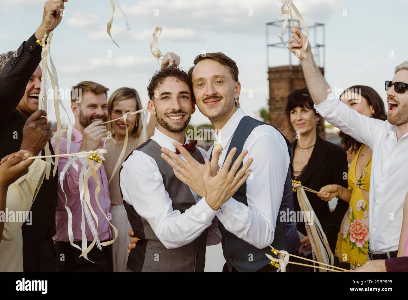 Ritratto della coppia gay appena sposata che mostra gli anelli alla cerimonia di nozze Foto Stock