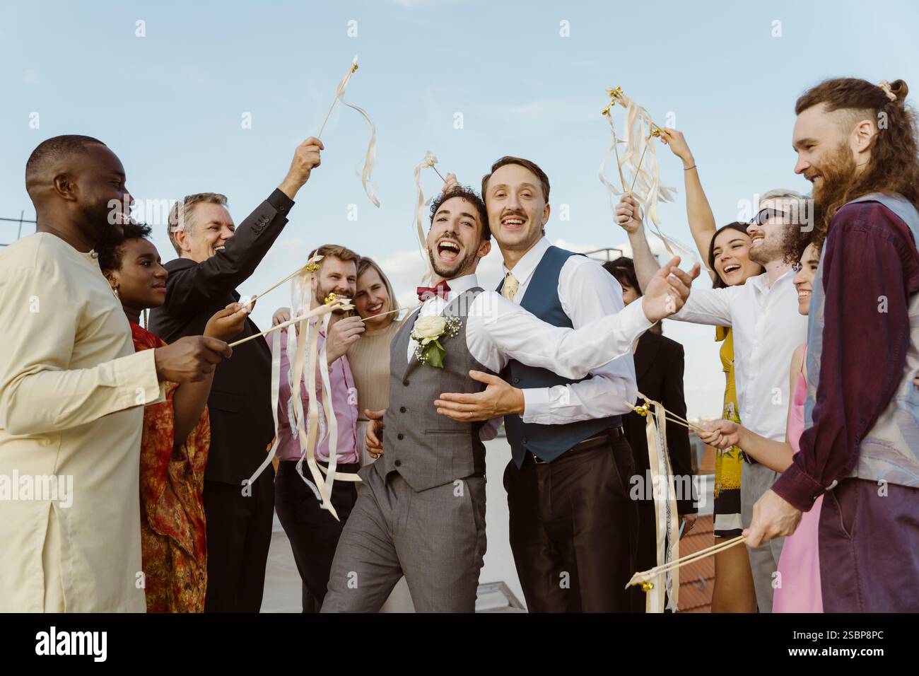 Coppia gay felice che si diverte con gli ospiti alla cerimonia di nozze sul tetto Foto Stock