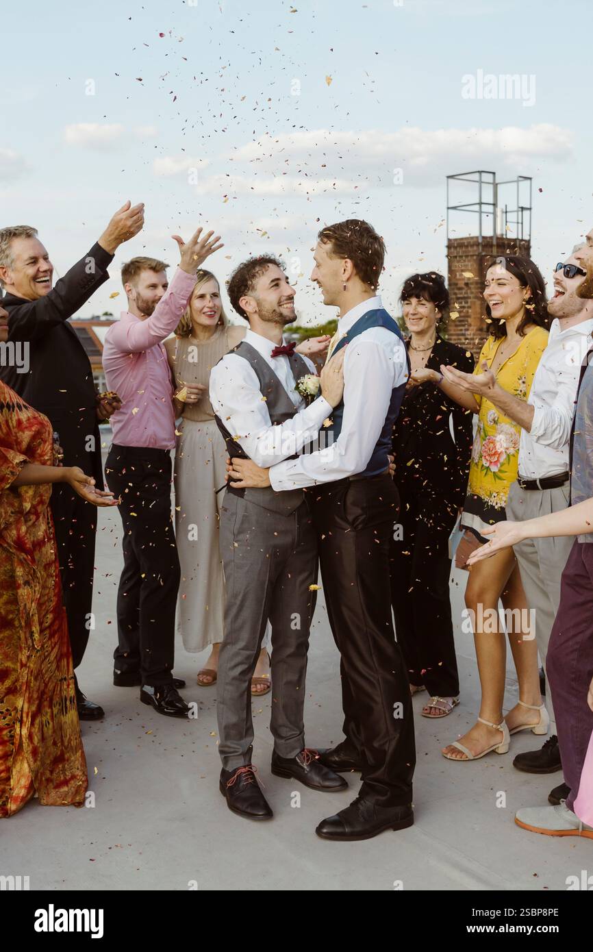Ospiti che lanciano coriandoli su coppie gay appena sposate Foto Stock