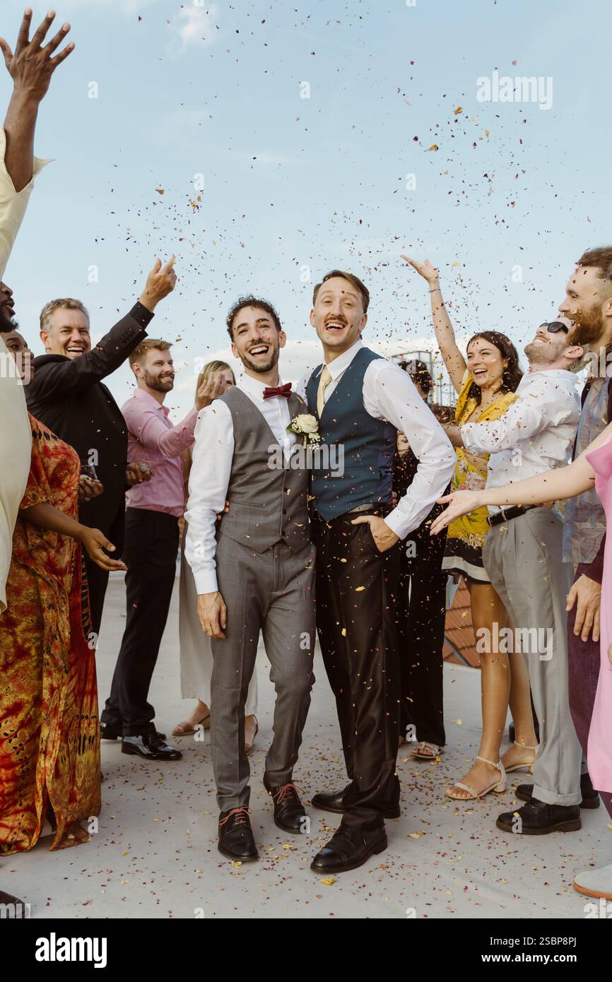 Felice coppia gay che si diverte con gli ospiti durante la cerimonia di nozze sul tetto Foto Stock