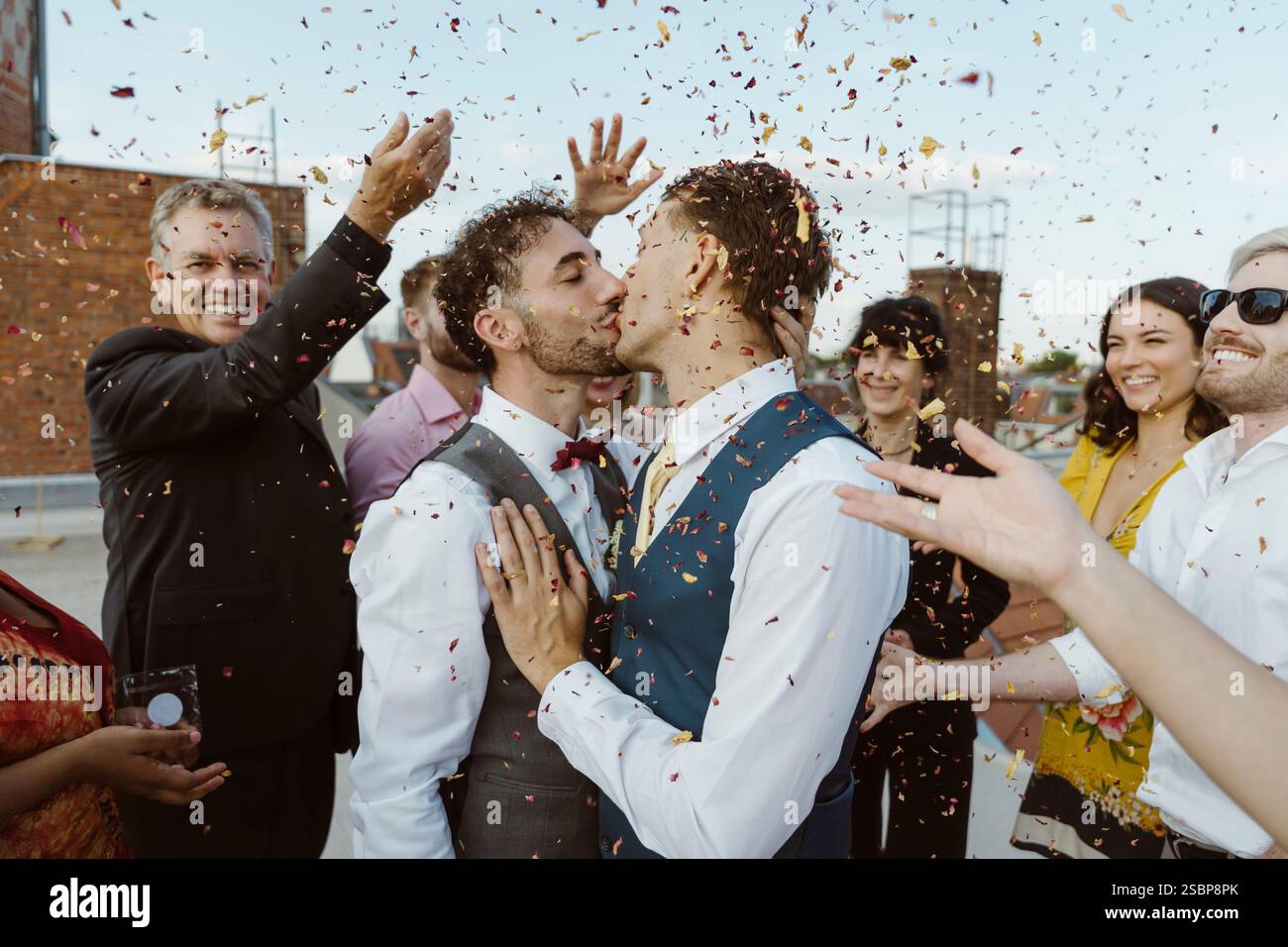 Amate coppie gay che si baciano e ospiti che lanciano coriandoli durante la cerimonia Foto Stock